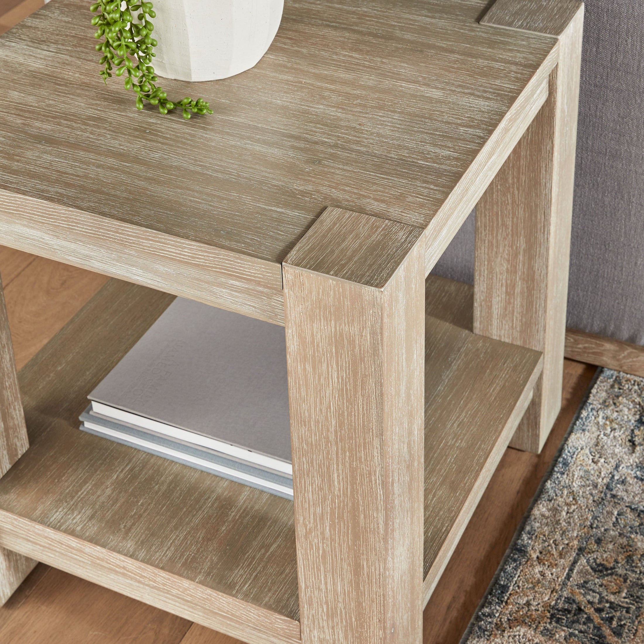 Close-up of Adler End Table in light wood finish with lower shelf holding books by Essentials for Living