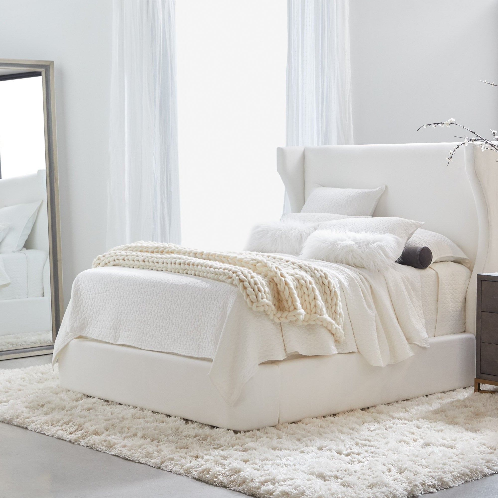Balboa Queen Bed with curved wingback headboard and piped edges in light fabric by Essentials For Living