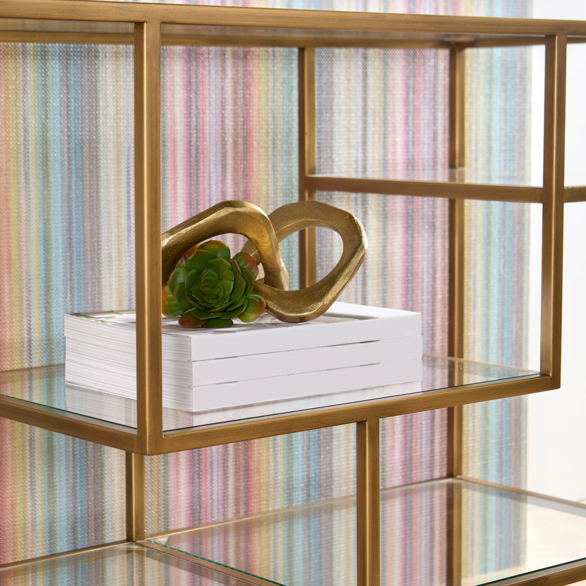 Beakman Low Bookcase with brass frame and clear glass shelves showcasing decor, by Essentials for Living.