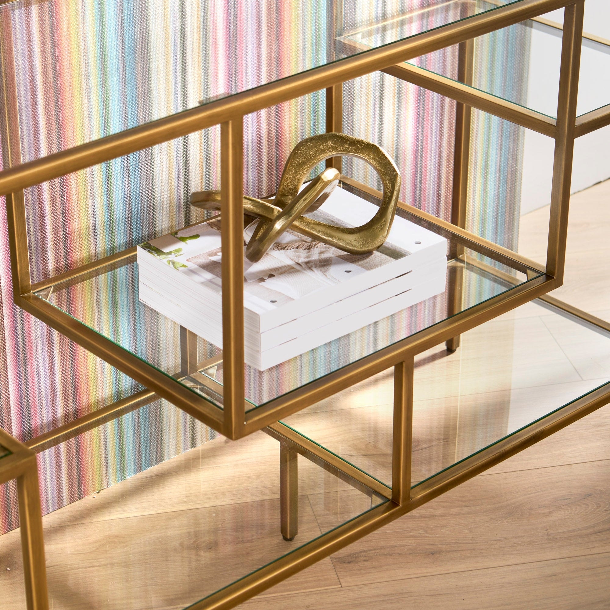 Beakman Low Bookcase with brass metal frame and clear glass shelves showcasing decor by Essentials for Living