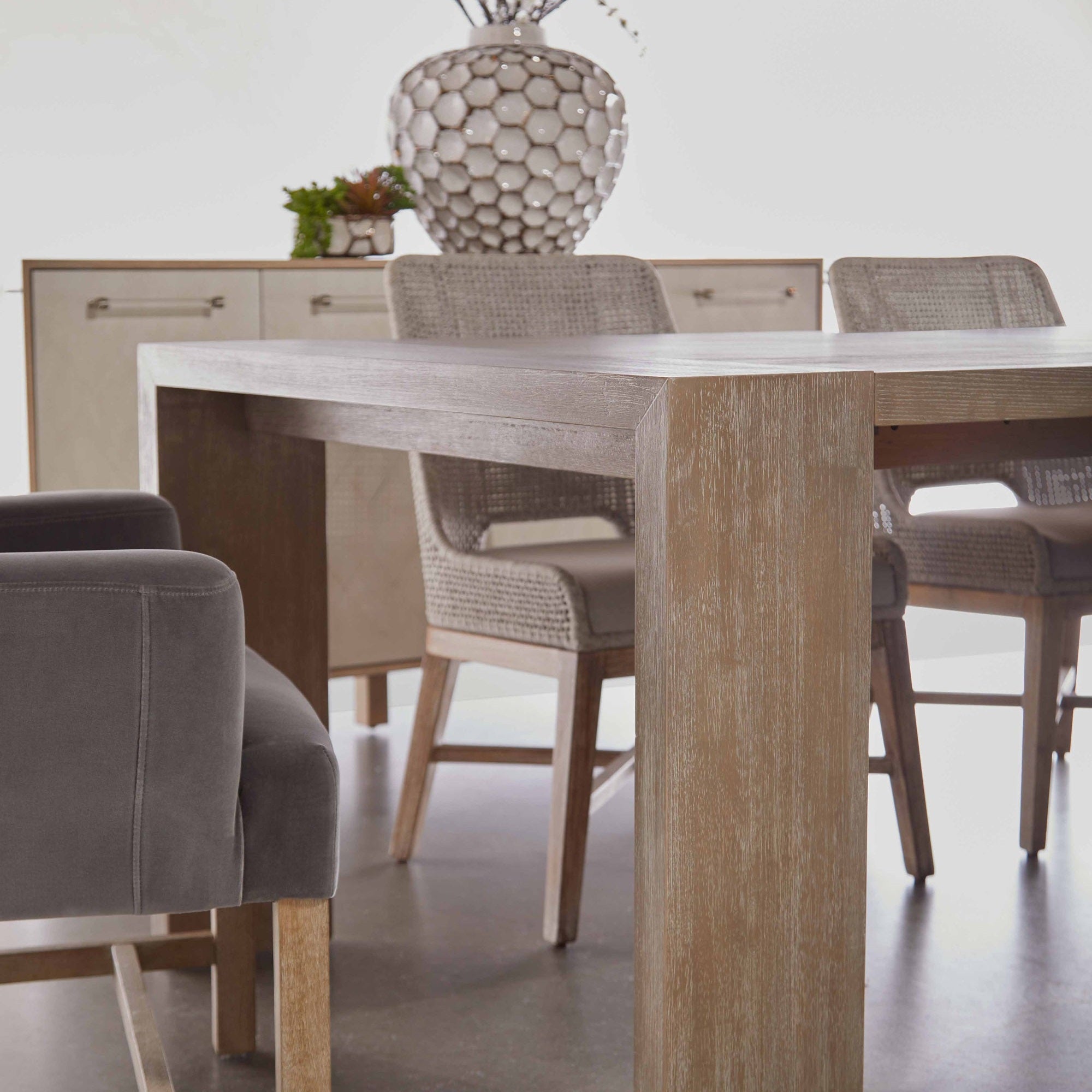 Bennett Arm Chair in dark caramel velvet with solid oak legs beside wooden dining table, Essentials for Living
