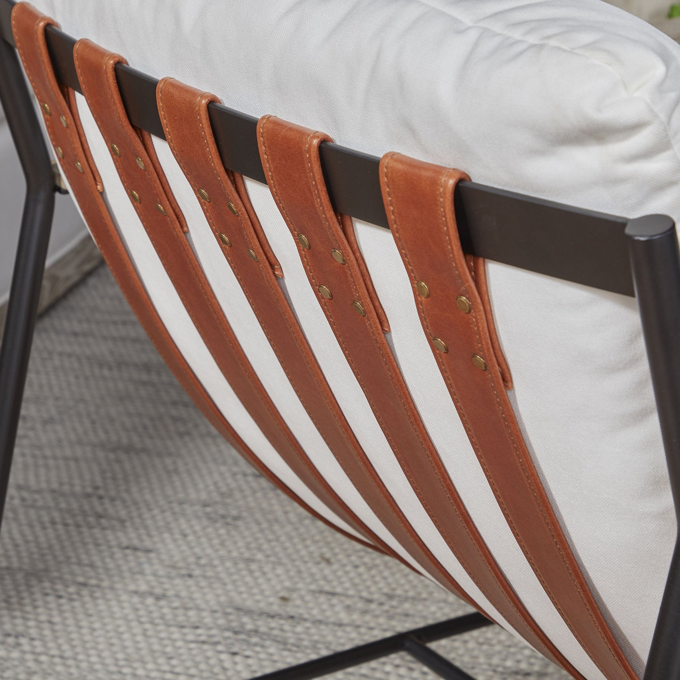 Close-up of Brando Club Chair leather straps and white cushions on black iron frame by Essentials For Living