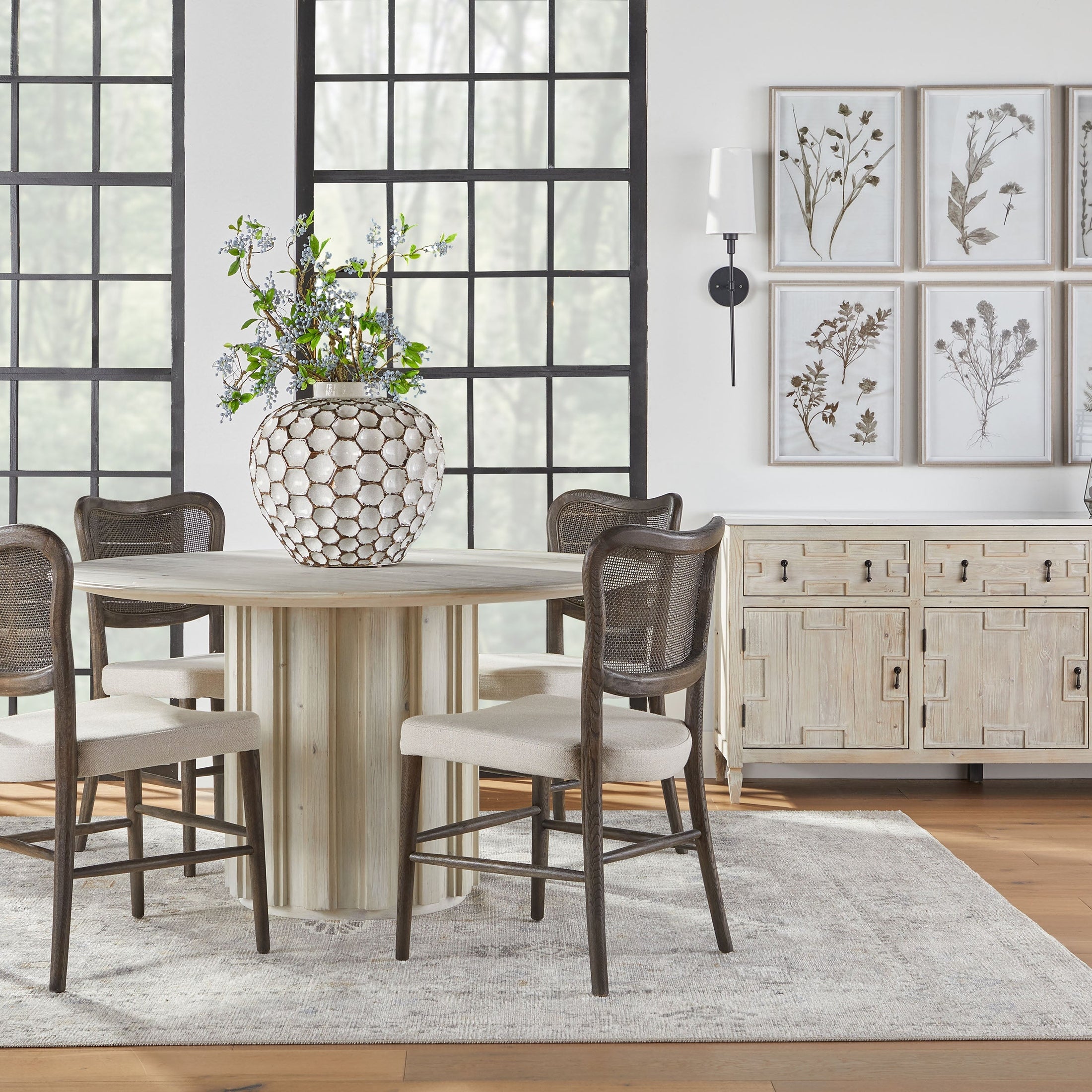 Essentials For Living Cela Dining Chair set of 2 with solid oak frame, handwoven cane back, and bisque upholstered seat in rustic dining room.