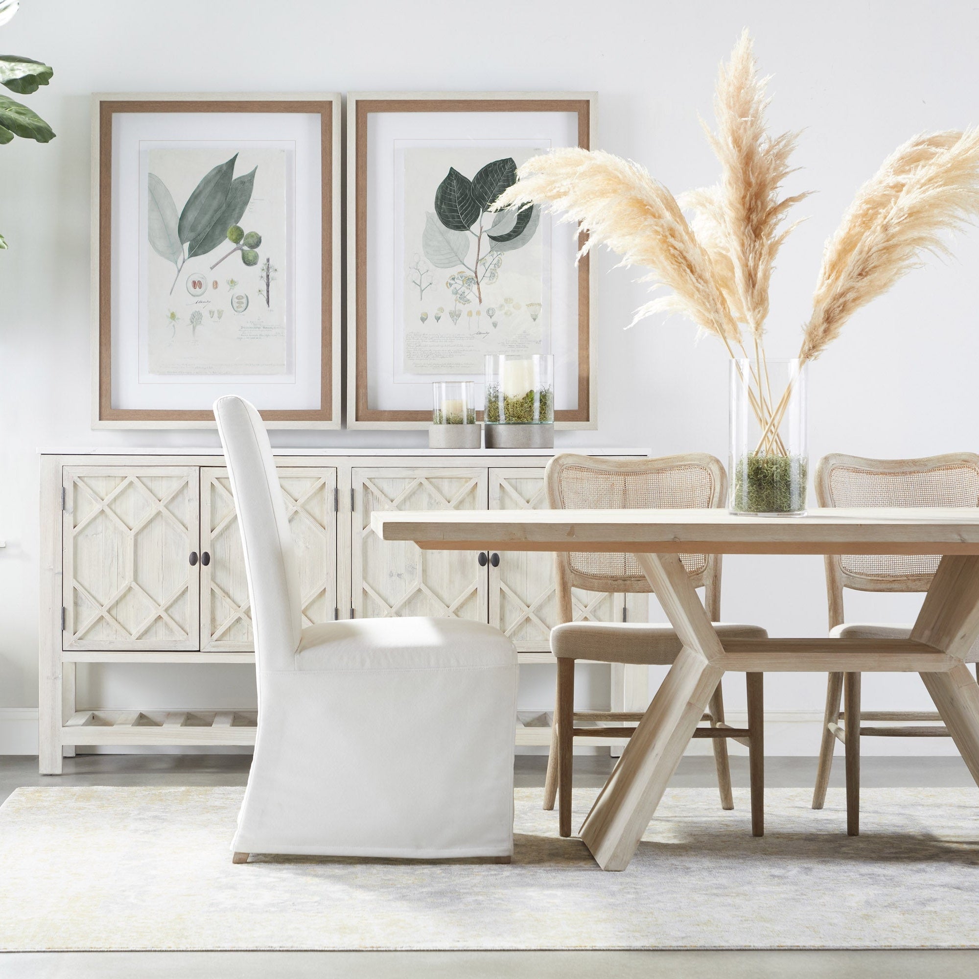 Two Cela Dining Chairs with solid oak frames and woven cane backs in a bright, modern dining room setting