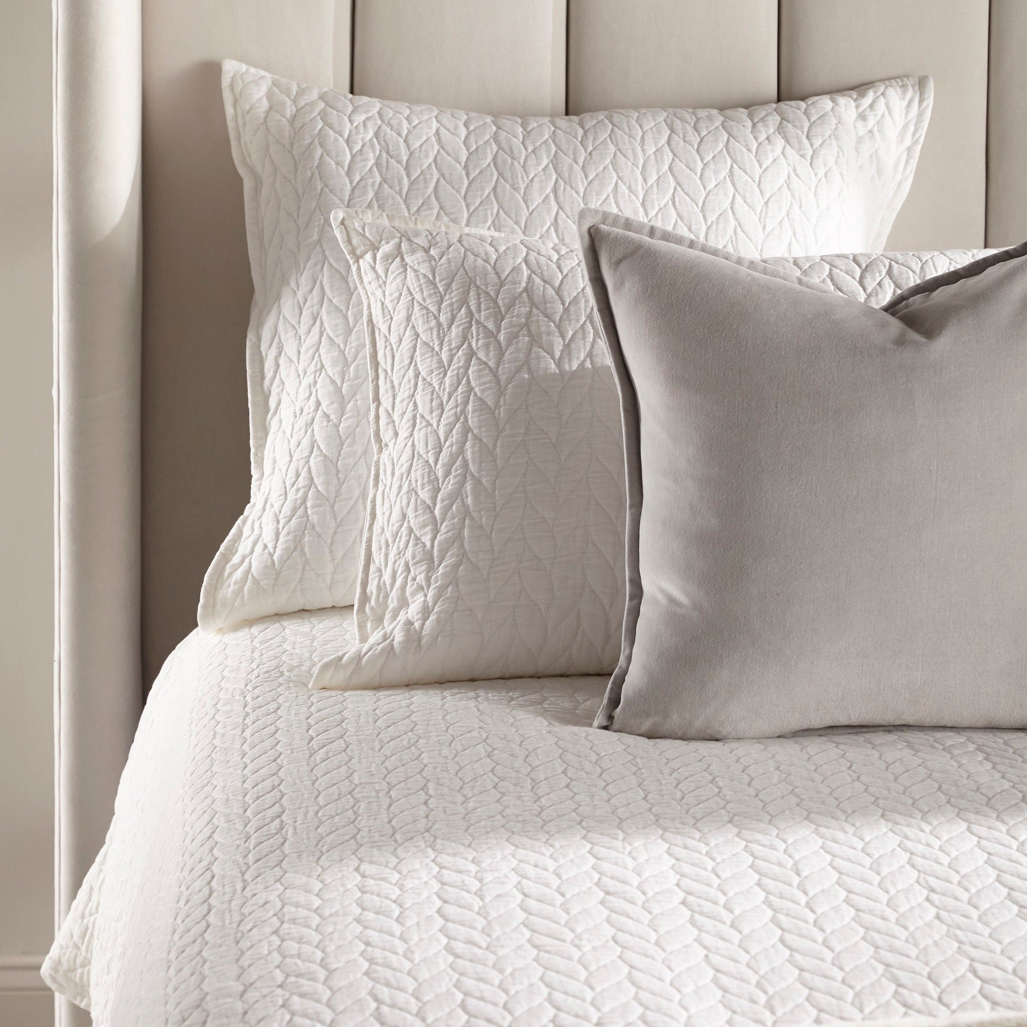 Close-up of Chandler Standard King Bed’s wingback headboard with cream velvet pillows and textured bedding by Essentials For Living