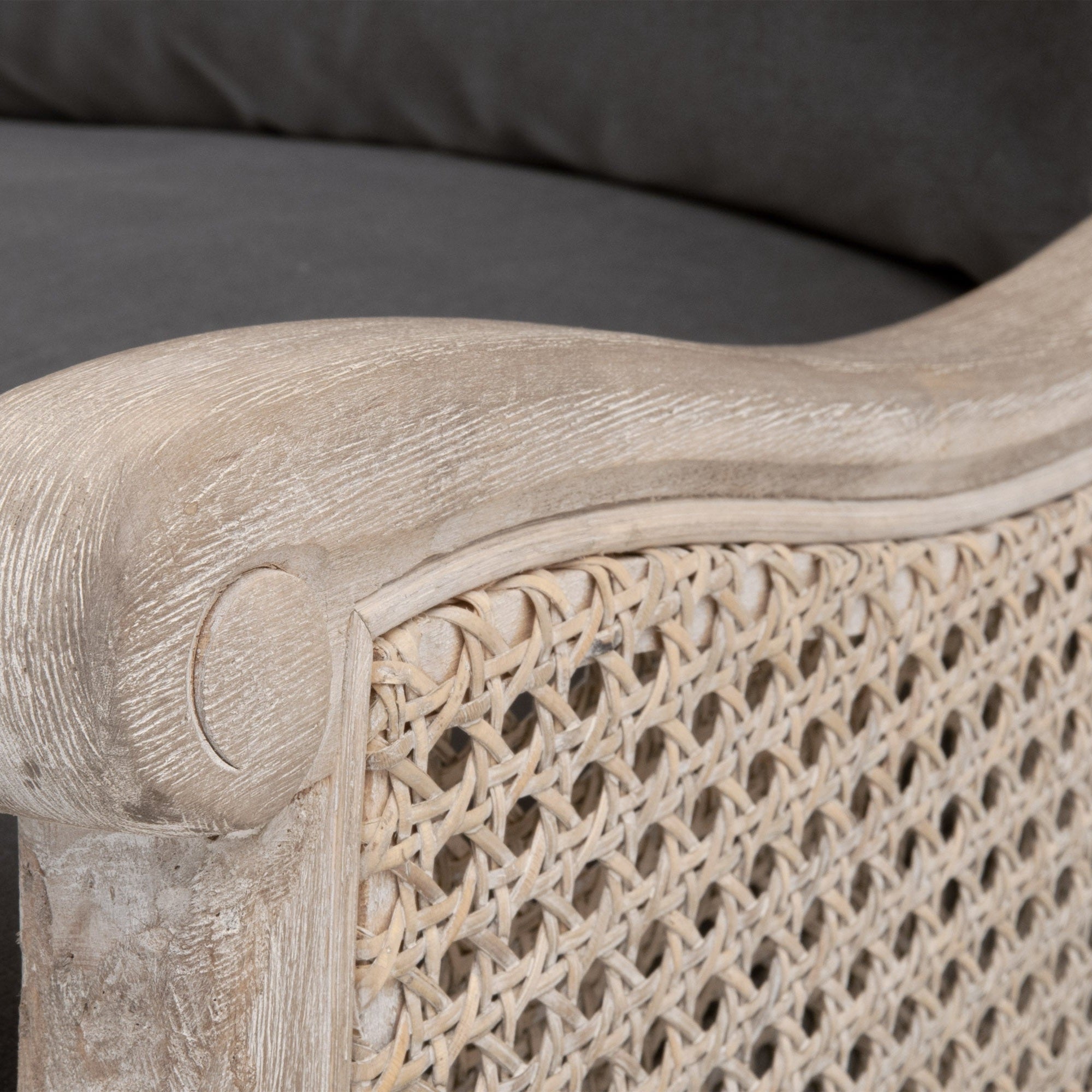 Close-up of Churchill Club Chair’s solid oak scroll armrest and woven rattan cane side in natural gray finish