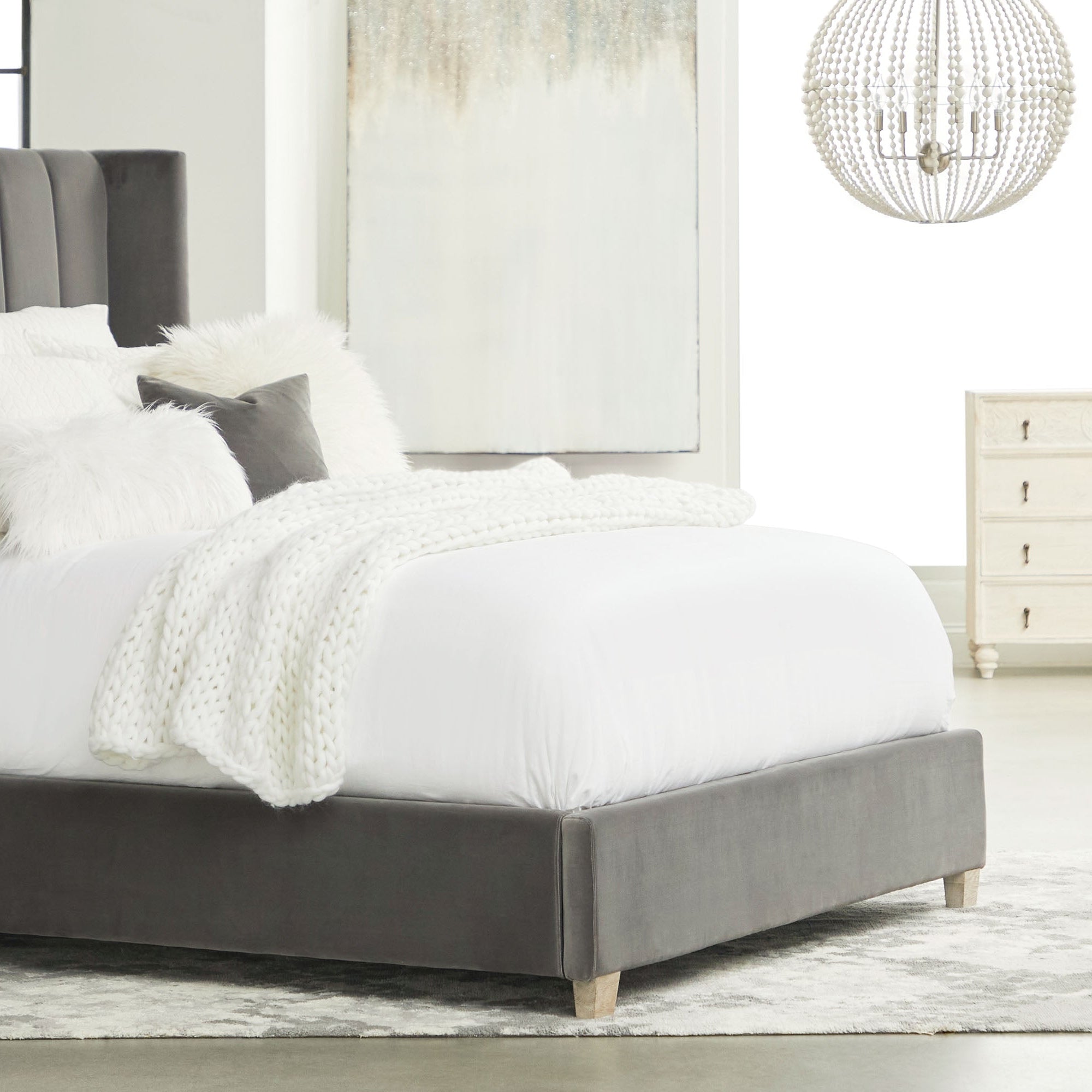Contemporary upholstered bed with gray fabric frame, tufted headboard, and plush white bedding in a bright modern bedroom