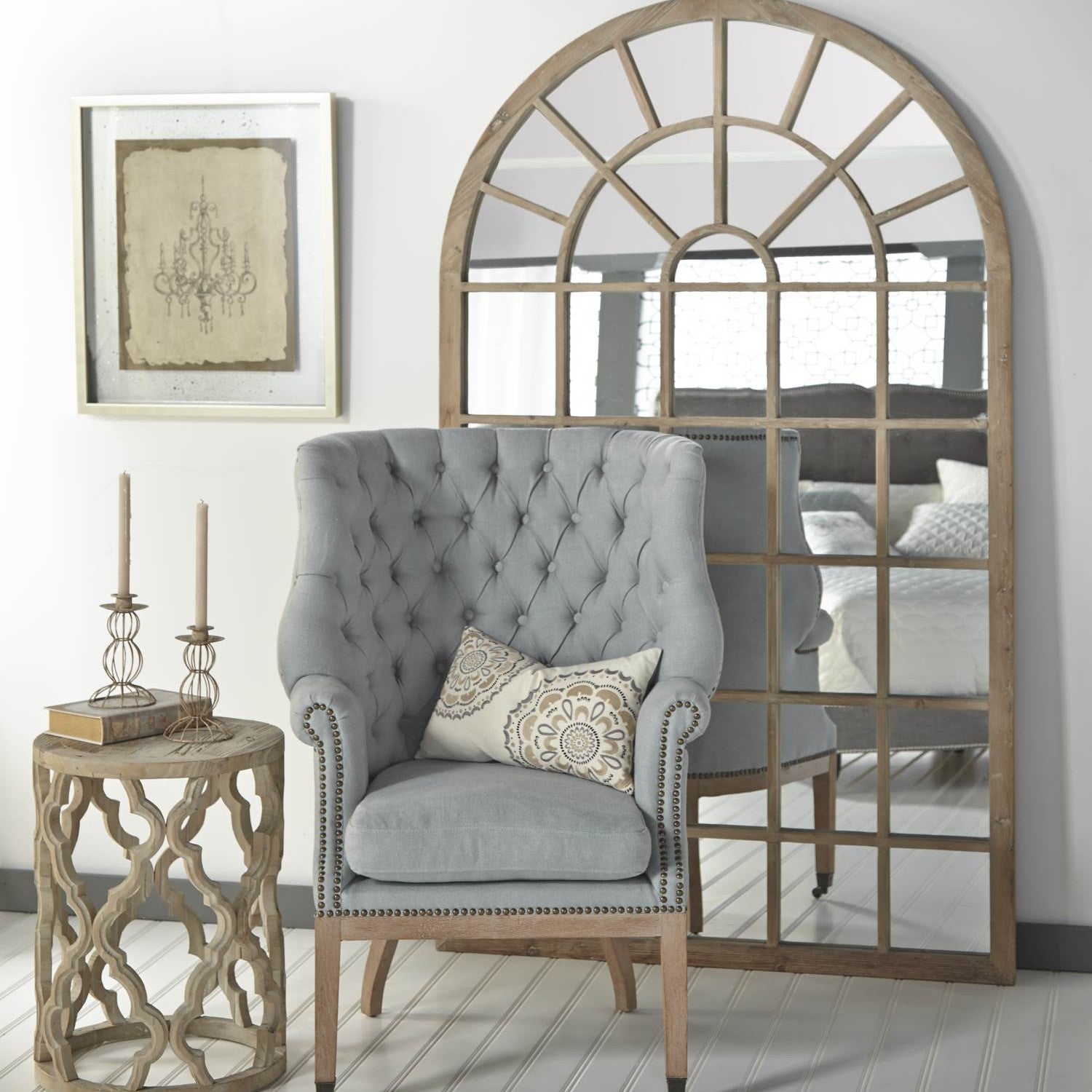 Essentials For Living Clover End Table in smoke gray reclaimed elm with carved quatrefoil base beside tufted armchair and large arched mirror