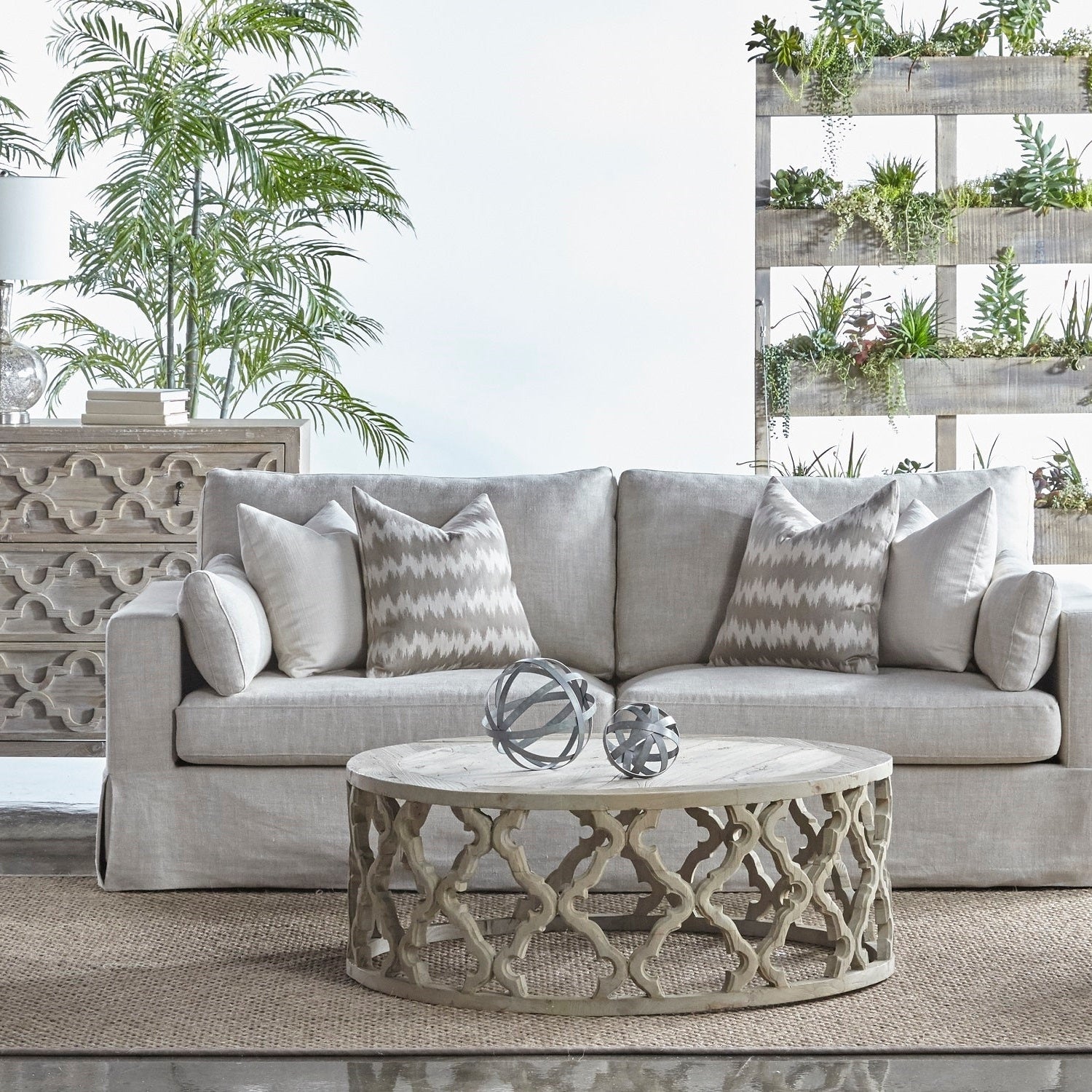Round coffee table with carved quatrefoil base in smoke gray reclaimed elm wood in cozy living room setting