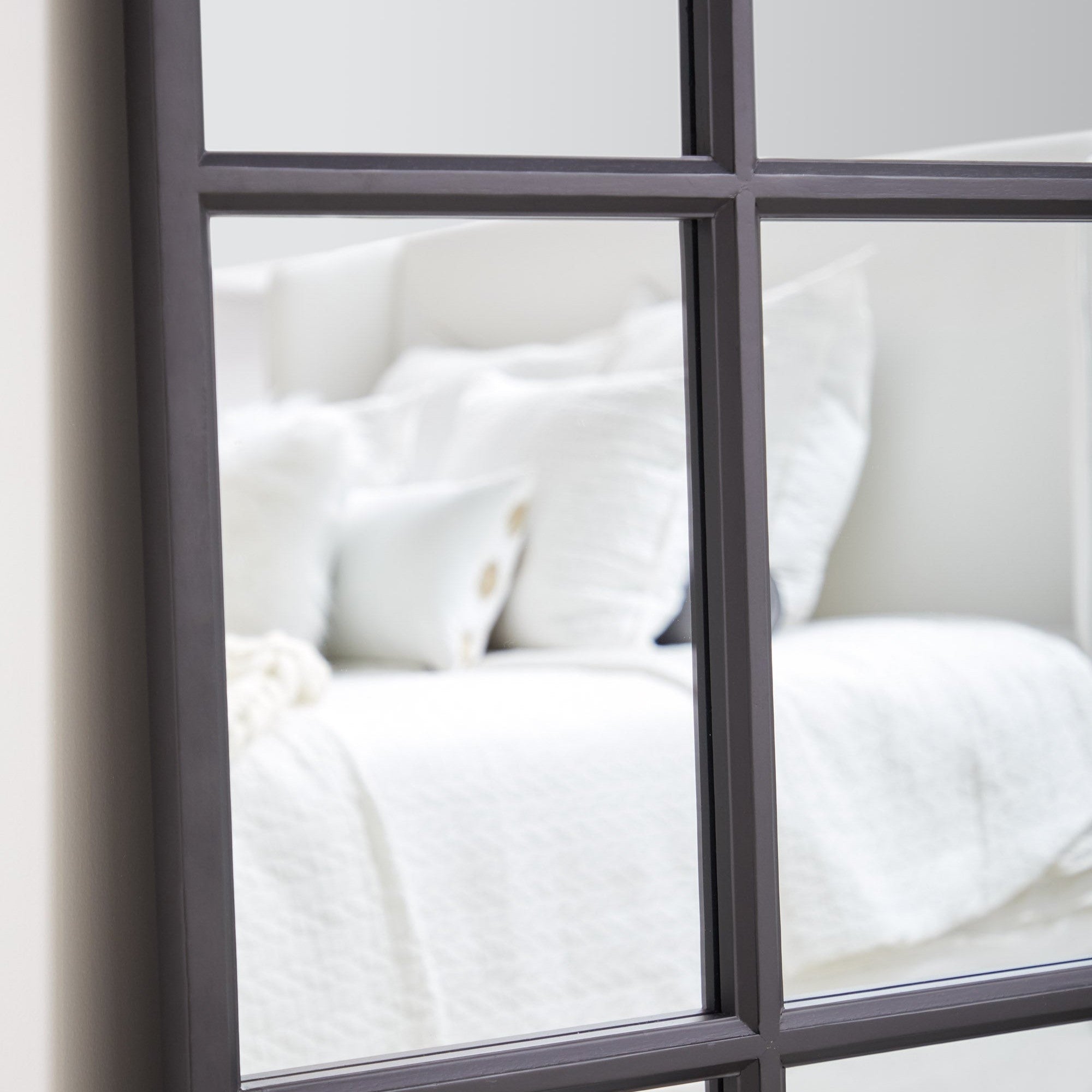 Close-up of the Grid Mirror with matte black oak grid frame reflecting a white couch by Essentials for Living