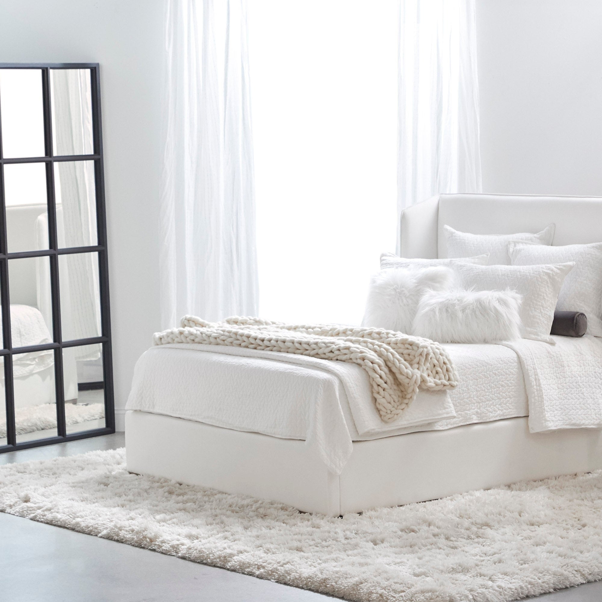 Grid Mirror with matte black oak frame leaning in bright bedroom next to white bed Essentials for Living