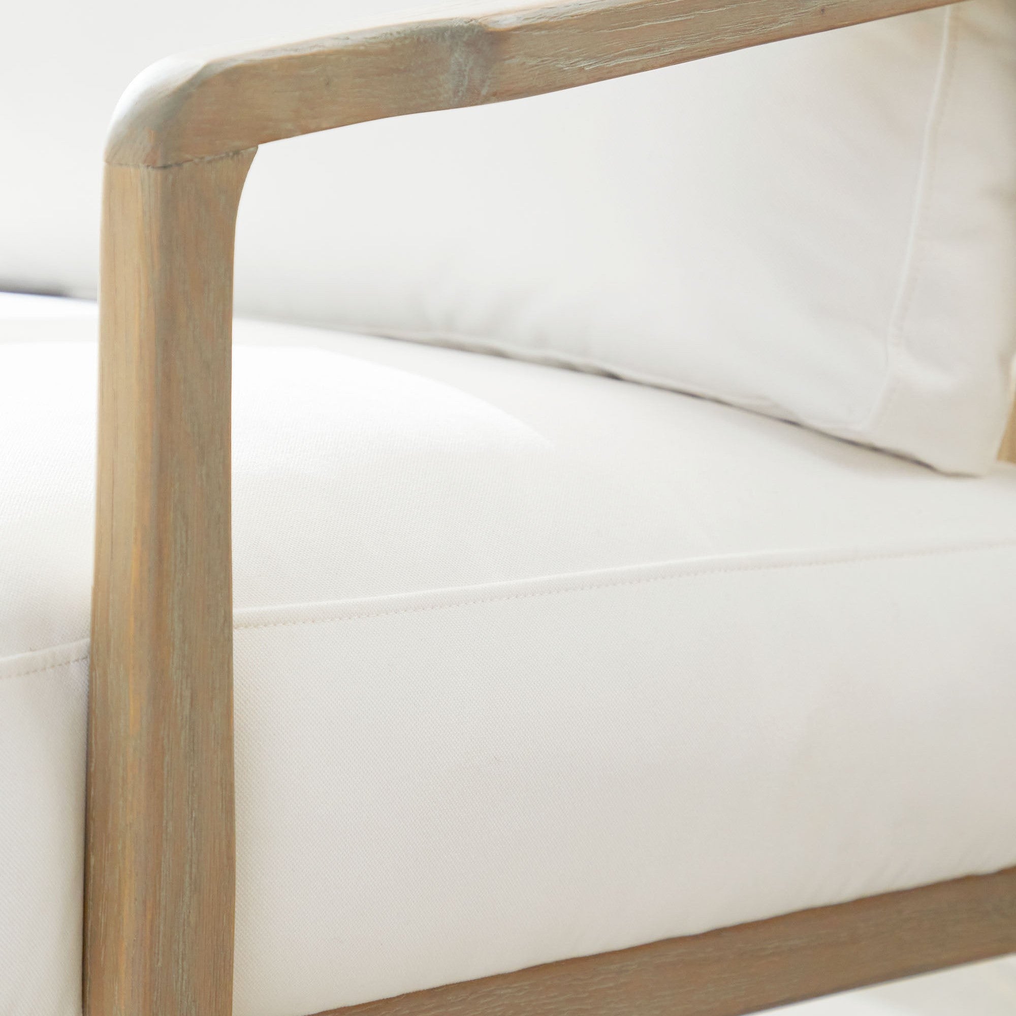 Close-up of Harbor Club Chair showing smooth curved smoke-gray oak frame and white upholstered cushions by Essentials for Living