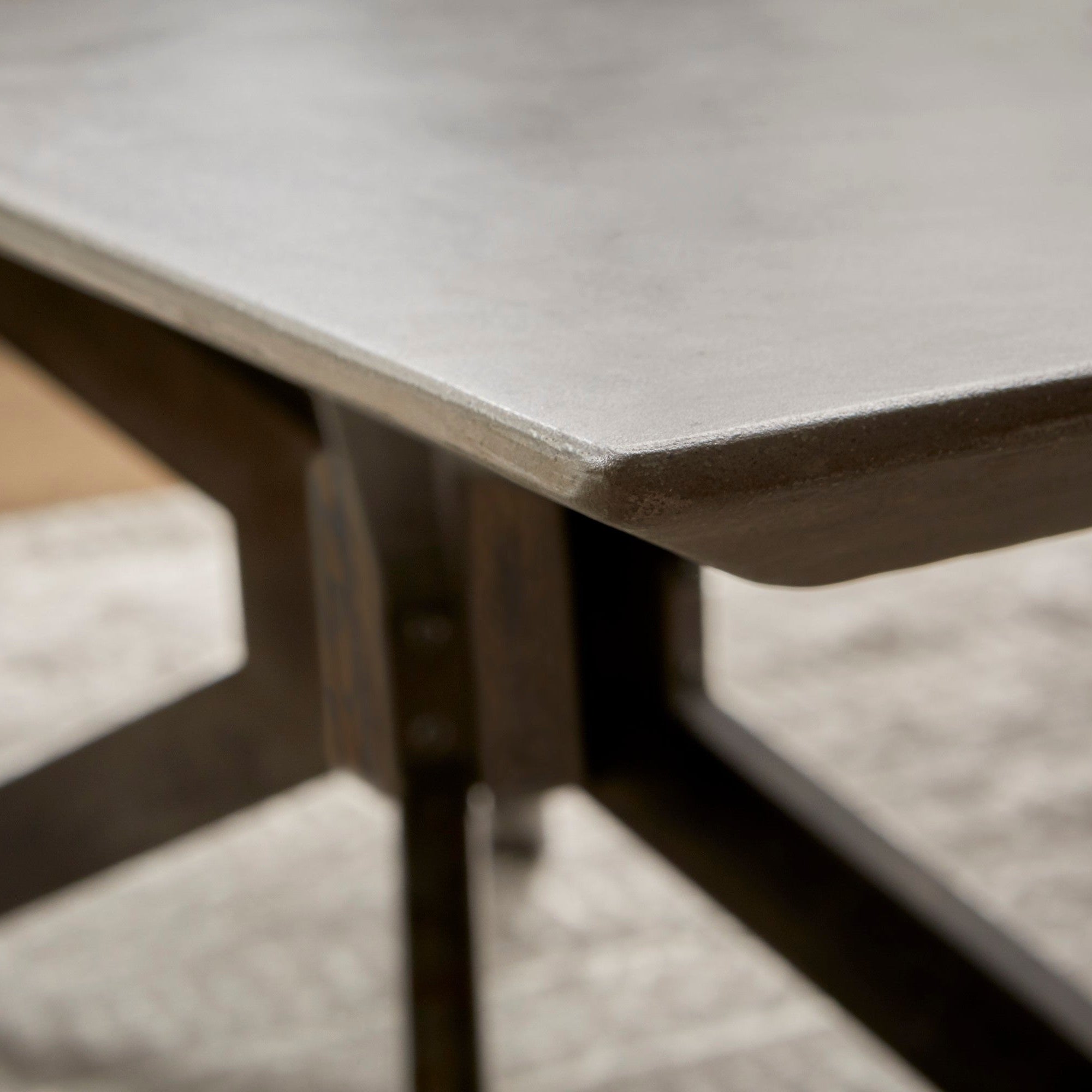 Close-up of Essentials for Living Industry Rectangle Dining Table corner with gray concrete top and black iron base