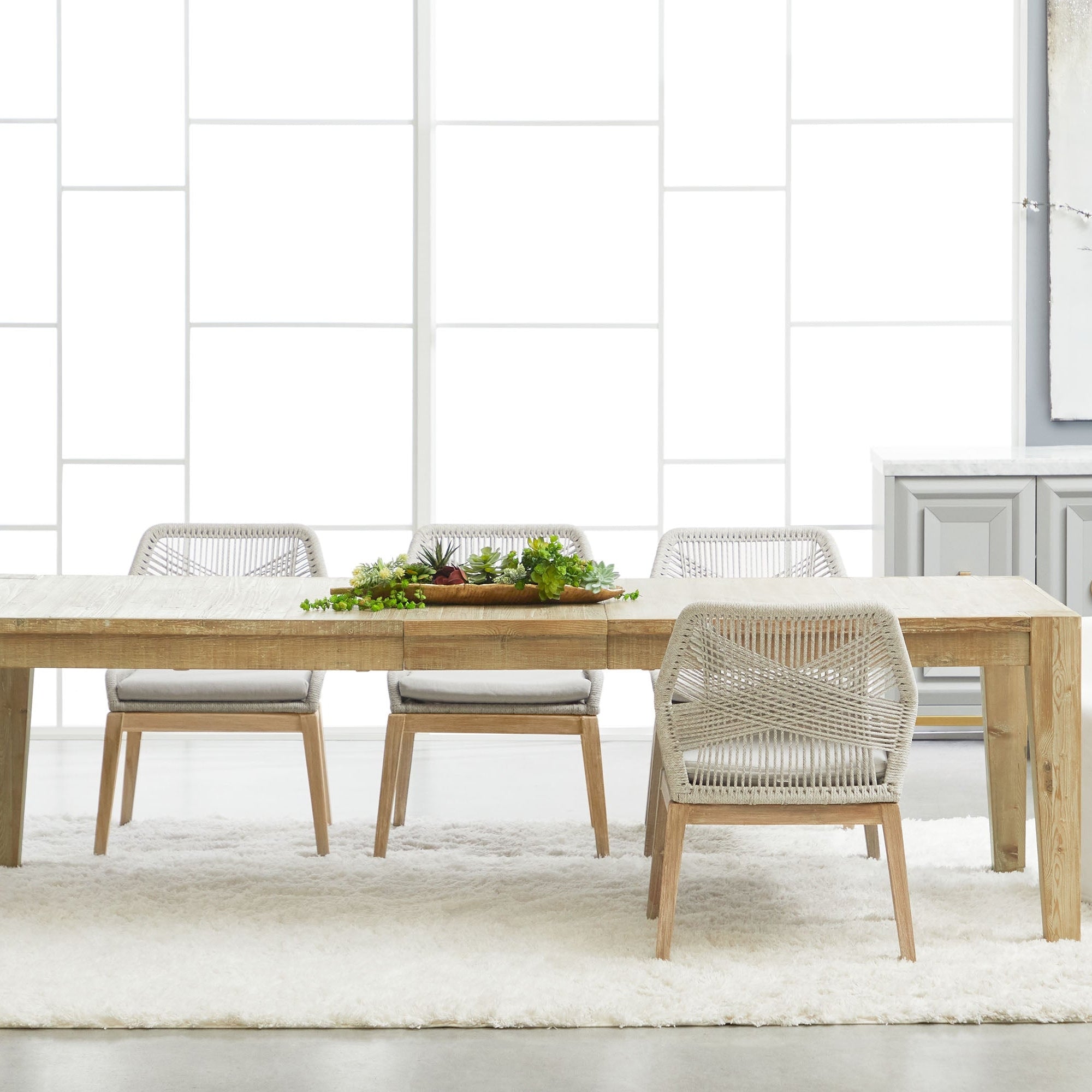 Set of two Essentials for Living Loom dining chairs with woven taupe and white rope and wooden legs around light wood table