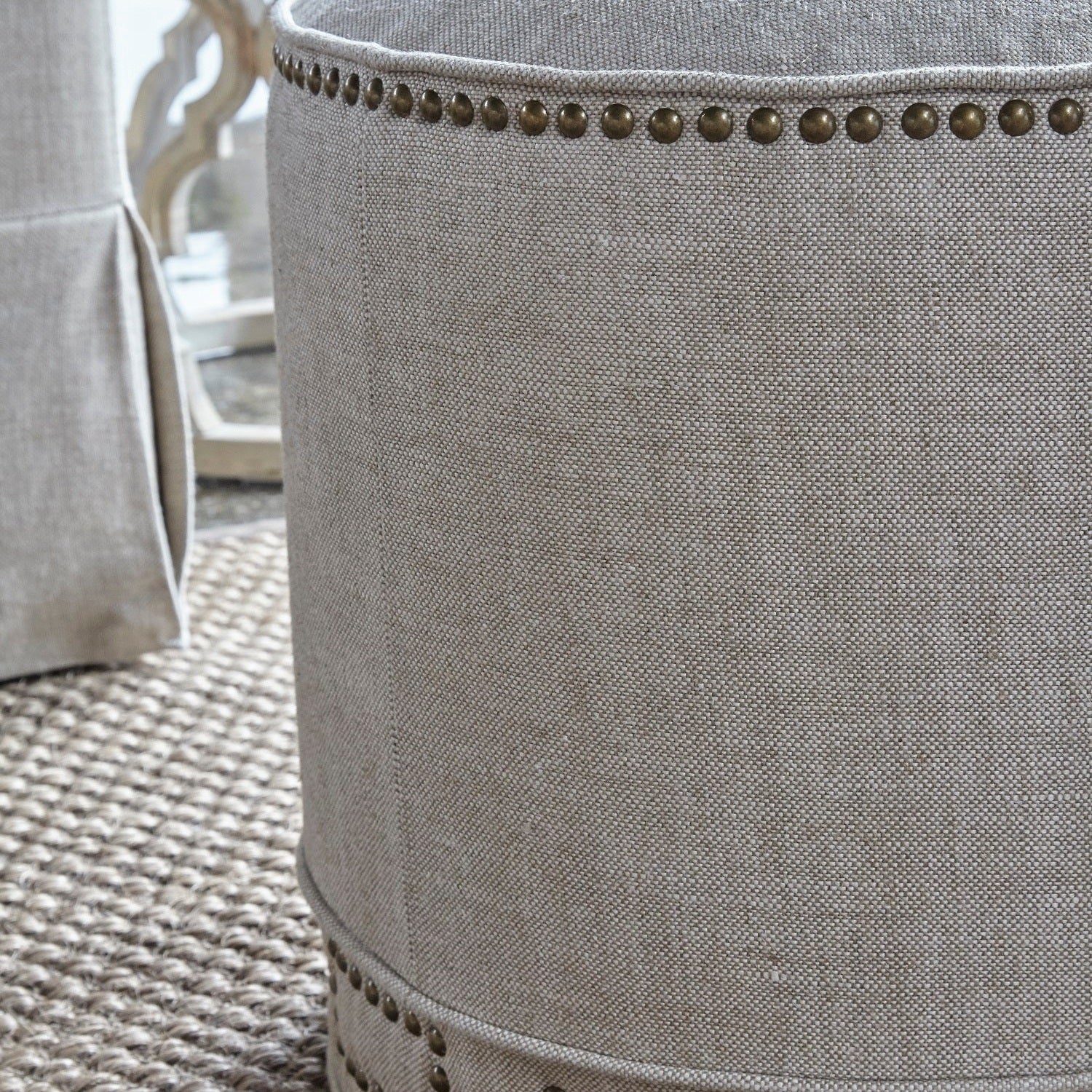 Close-up of Marlow Ottoman in bisque linen with gold nailhead trim by Essentials for Living.