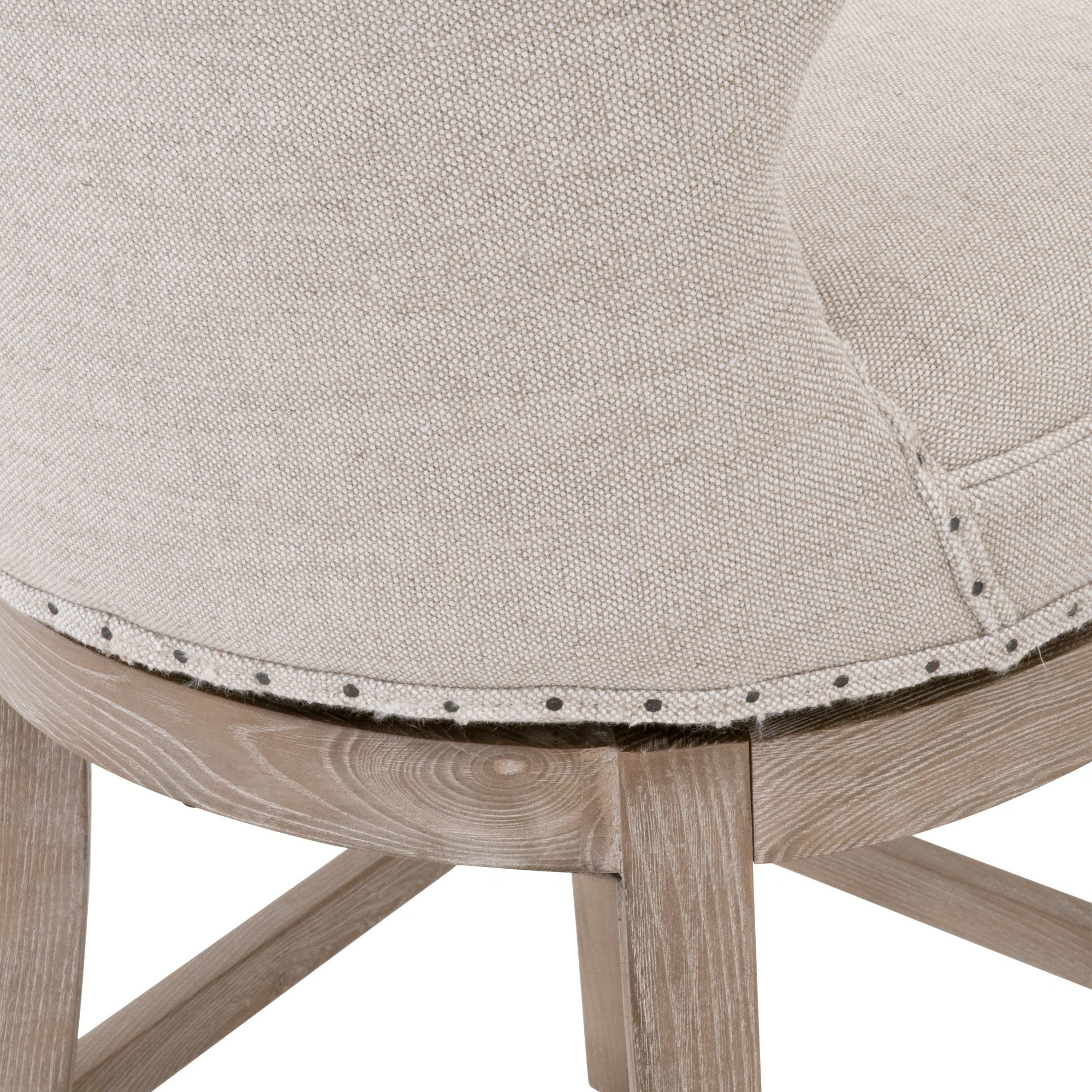 Close-up of beige linen upholstered seat with black nail-tack trim and natural gray ash-wood frame on swivel counter stool
