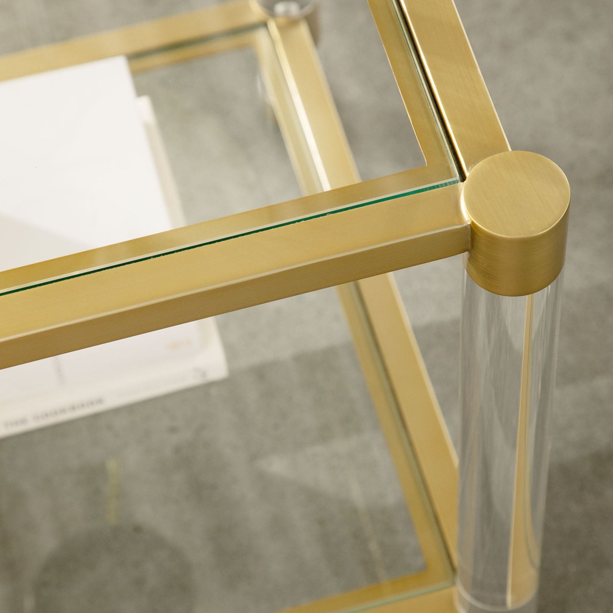 Close-up of the Nouveau End Table showing brushed brass frame and clear glass with Lucite legs by Essentials For Living