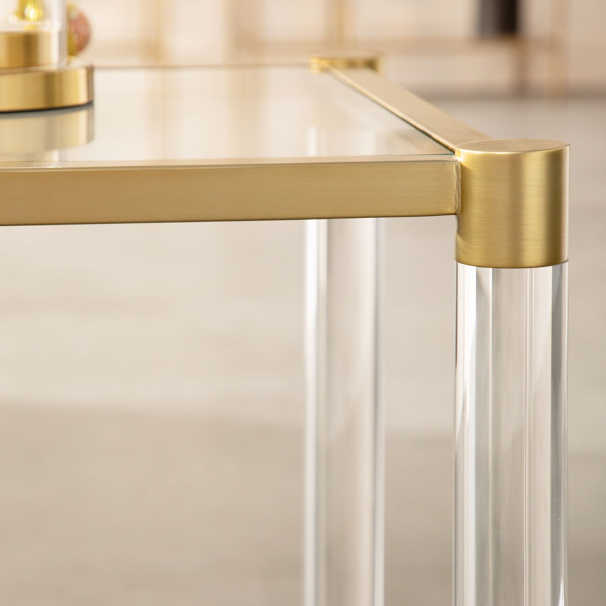 Close-up of brushed brass frame and clear Lucite legs on Nouveau End Table by Essentials for Living.