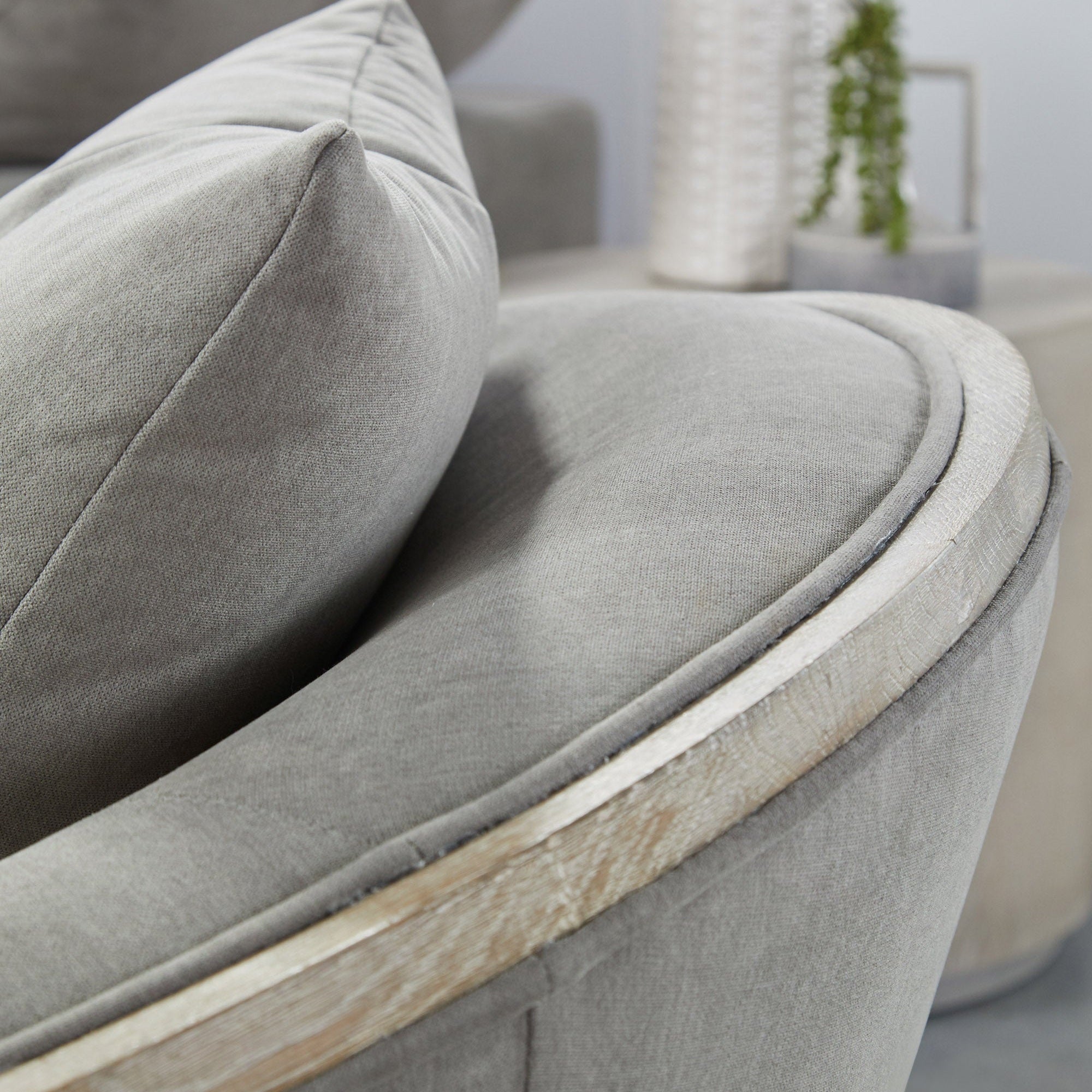 Close-up of gray Paxton Swivel Club Chair showing soft fabric upholstery and natural gray oak trim detail