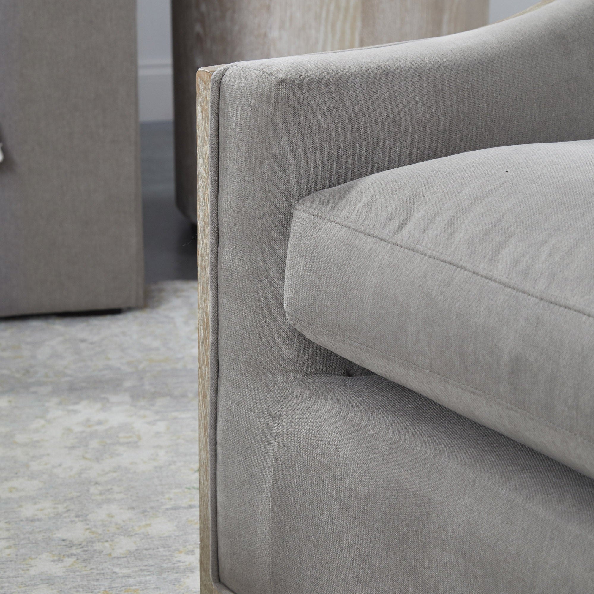Close-up of the Paxton Swivel Club Chair arm showcasing gray fabric upholstery and natural oak trim by Essentials For Living