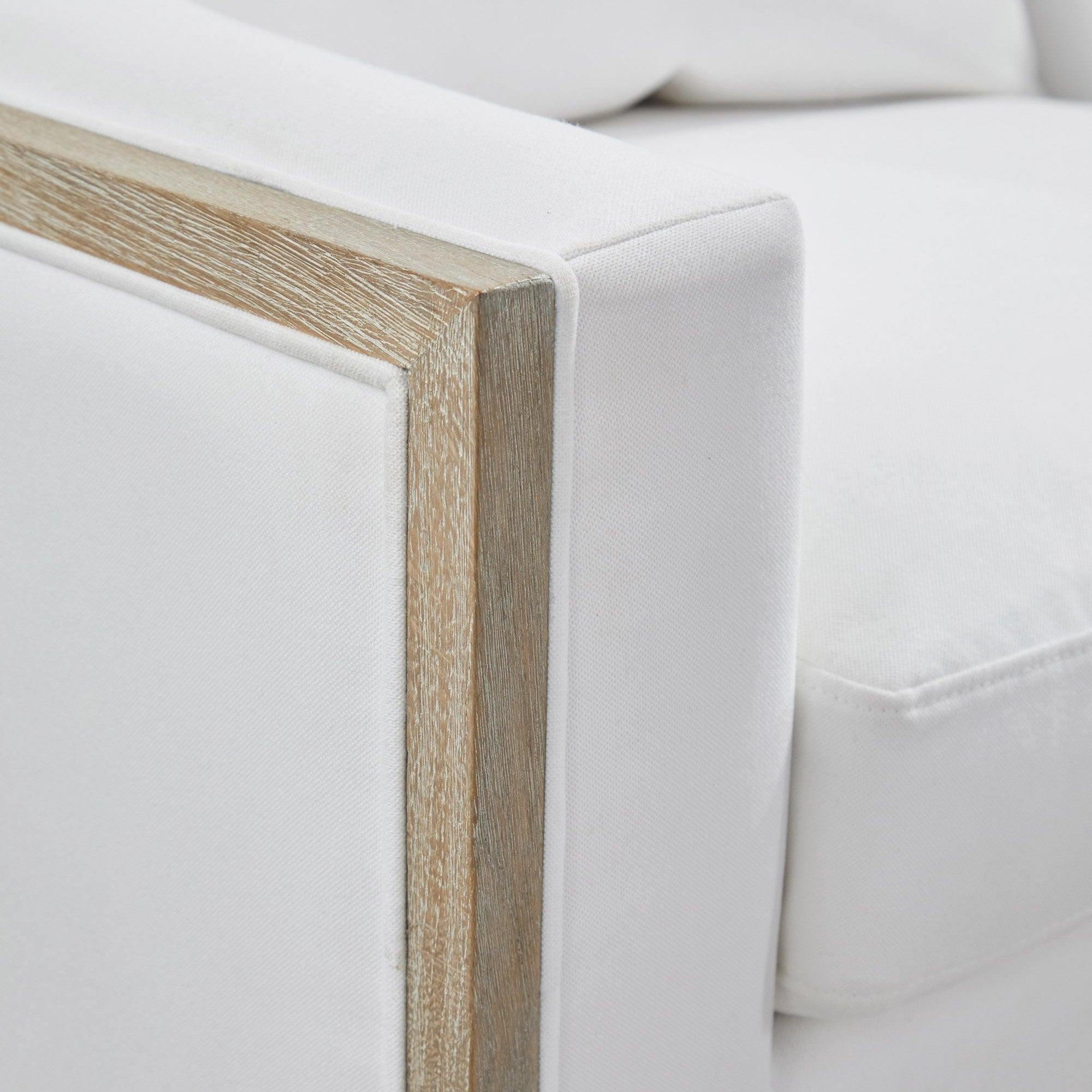 Close-up of white fabric and natural gray solid oak trim on the Paxton Swivel Club Chair by Essentials For Living