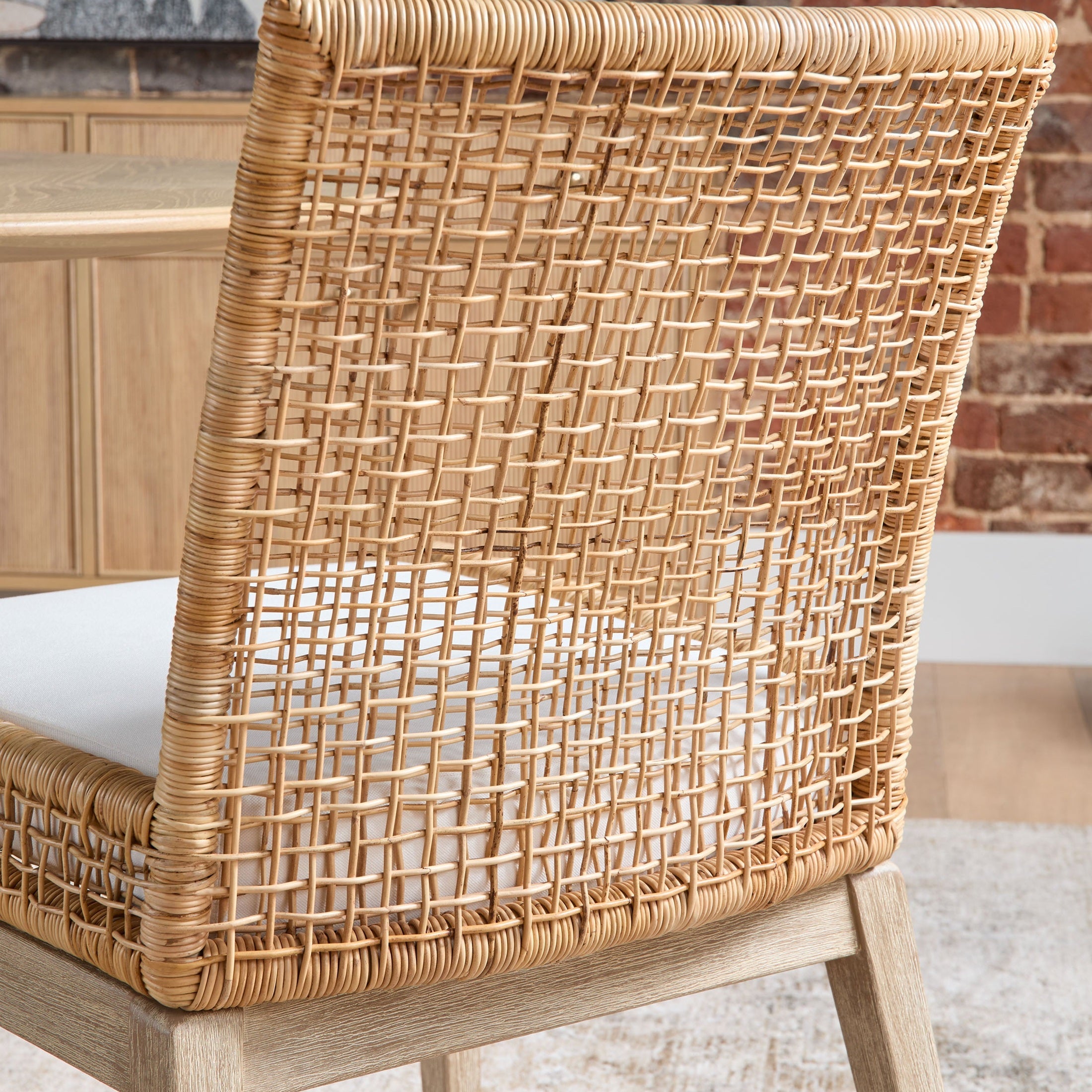 Close-up of Essentials for Living seaside dining chair showing handwoven natural rattan back and cushioned seat