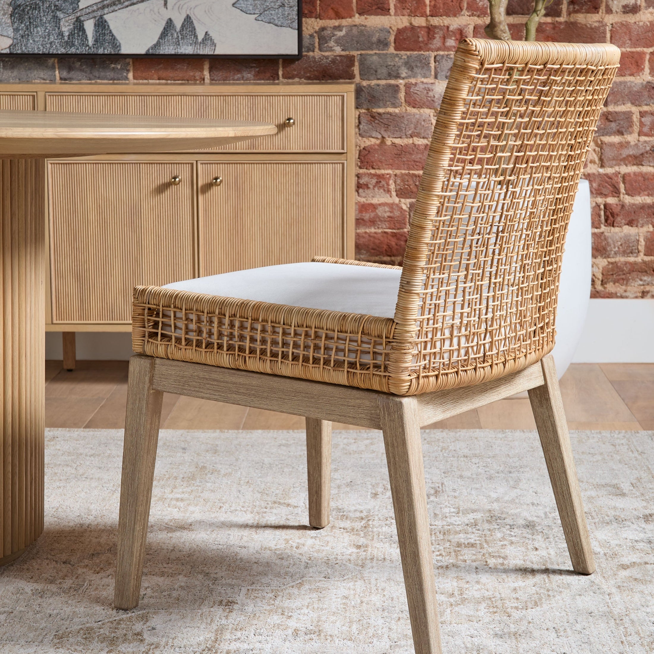 Essentials for Living seaside dining chair with handwoven natural rattan back and light gray mahogany frame in cozy room setting