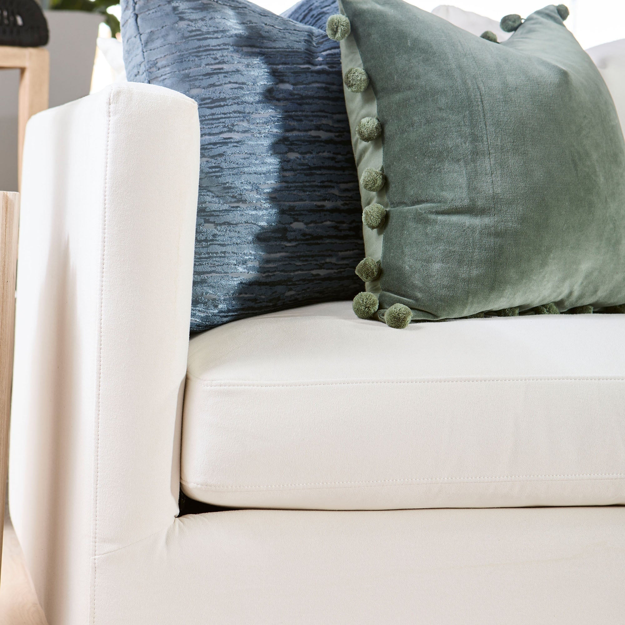 Close-up of Essentials for Living Siena 96" ivory sofa corner with plush blue and green decorative pillows
