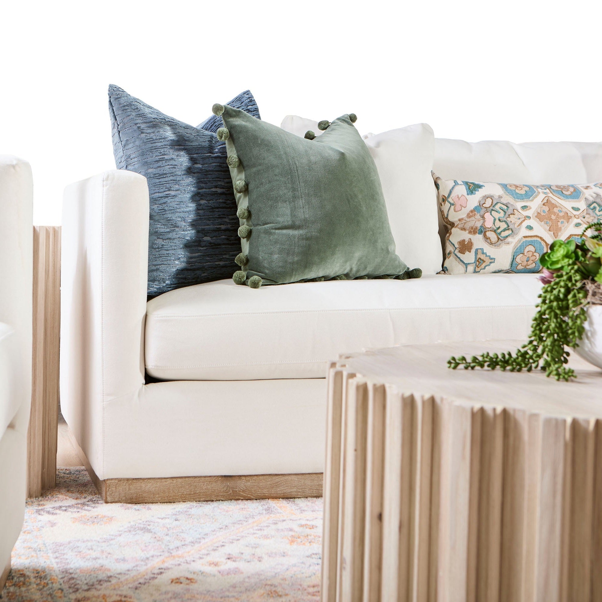 Ivory Siena 96 sofa by Essentials for Living with blue and green decorative pillows on a patterned rug