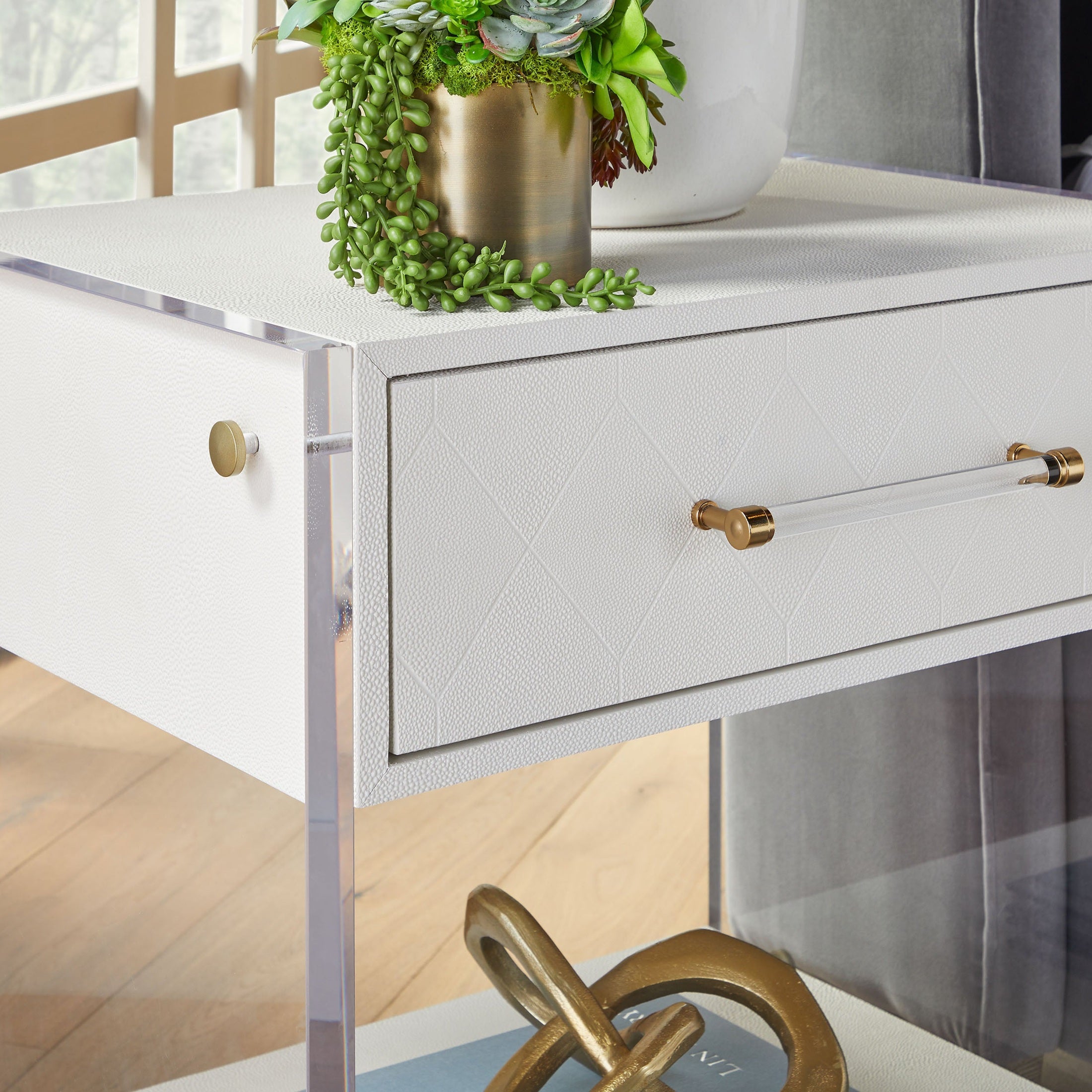 Pearl faux shagreen nightstand with clear acrylic sides and brass accents sitting in bright modern room by Essentials For Living