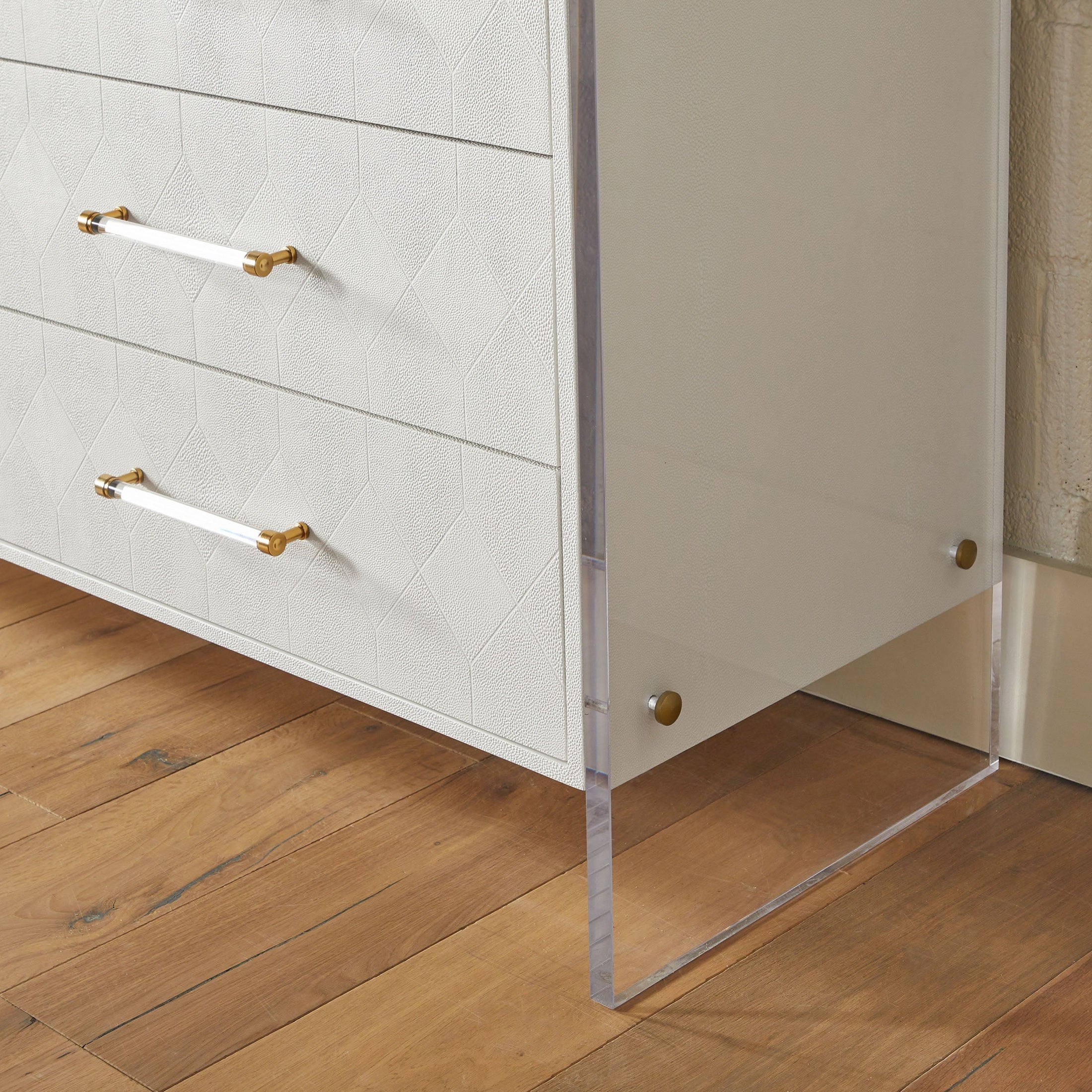 Close-up of pearl white faux shagreen dresser drawer with acrylic handle and clear acrylic leg on wood floor