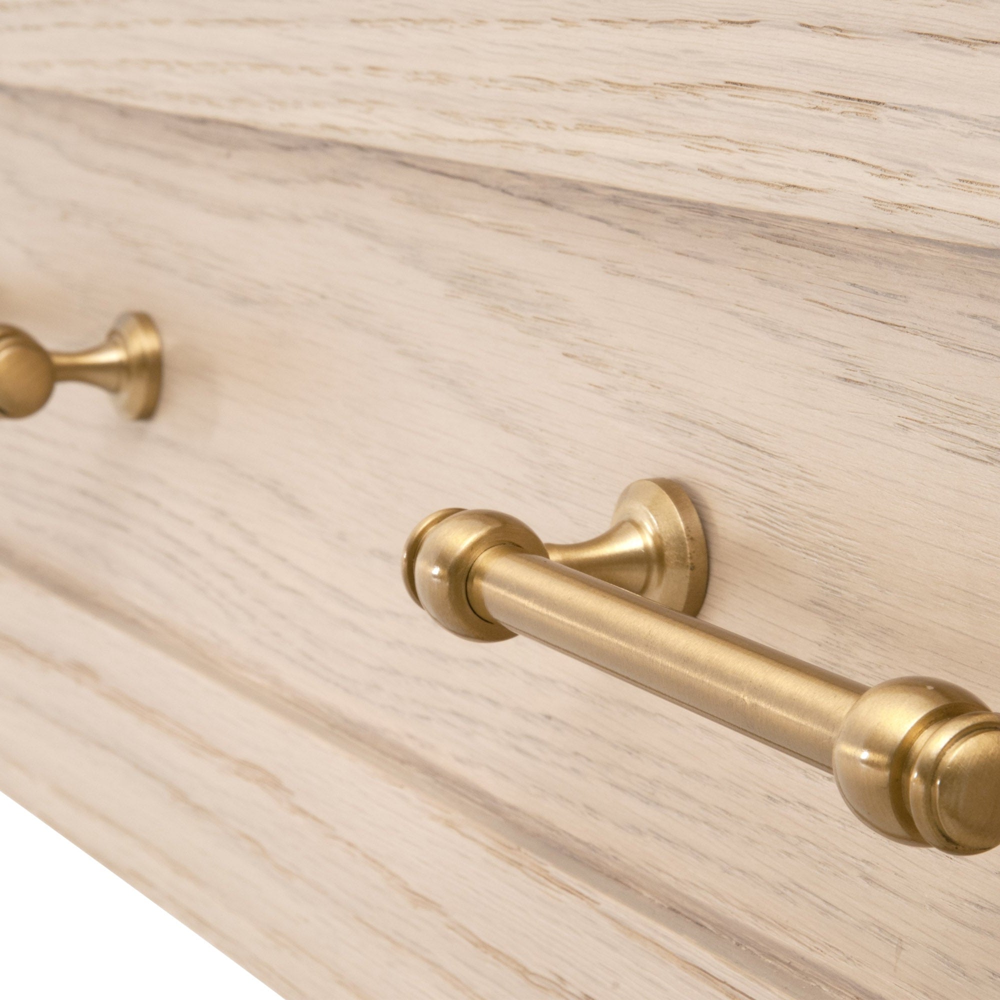 Close-up of brushed brass drawer handles on matte white lacquer solid rubberwood nightstand drawer