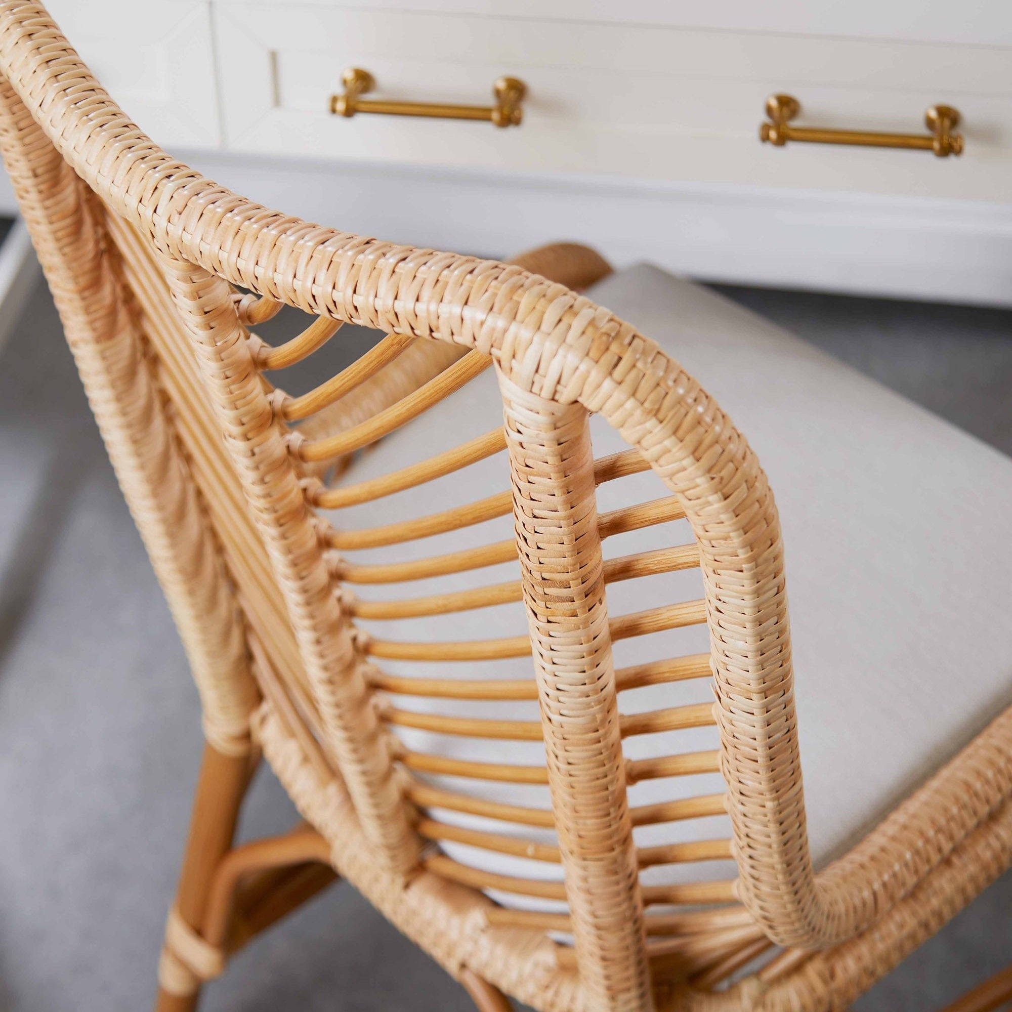 Close-up of woven rattan chair back with light cushioned seat in a stylish home office setting