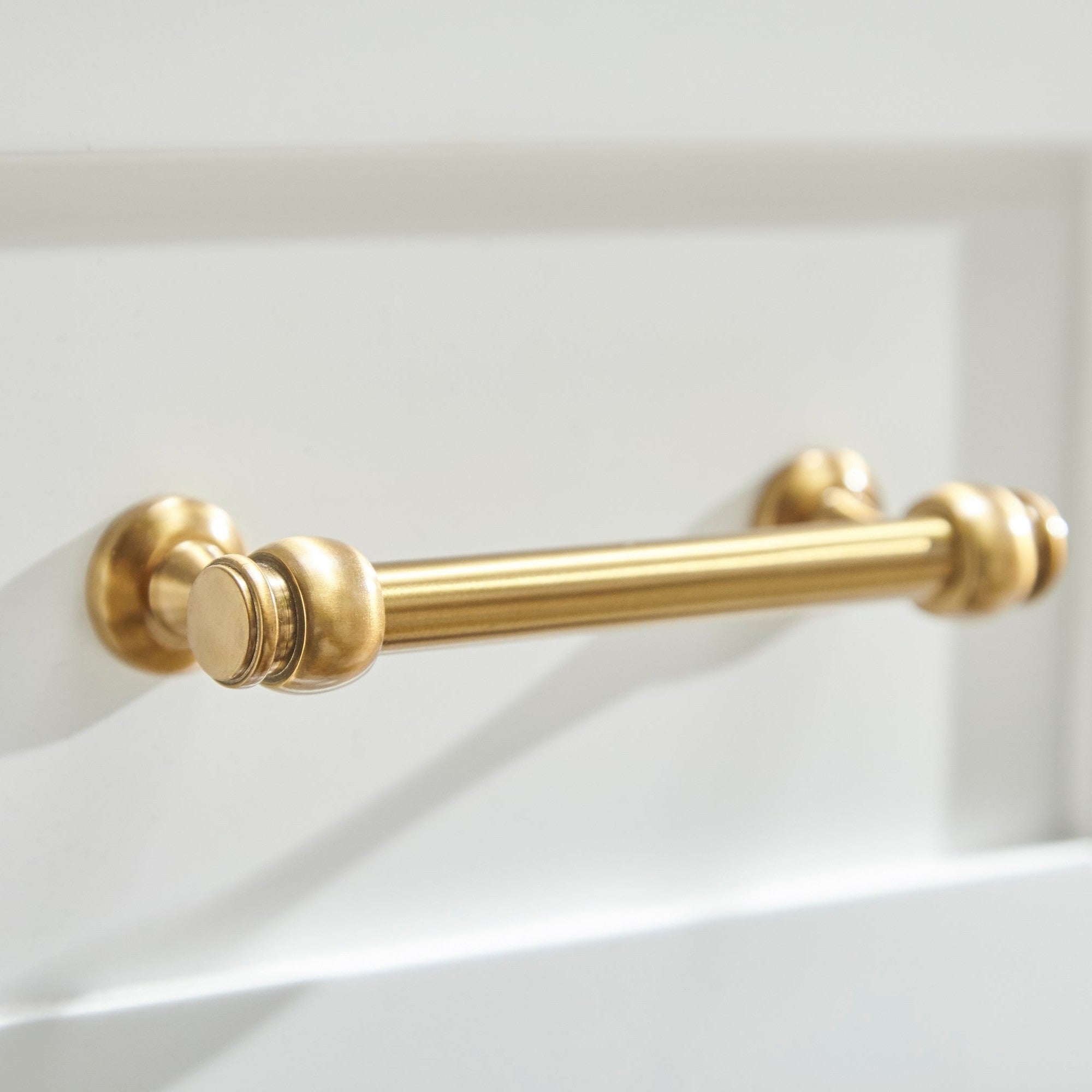 Brushed brass drawer handle on the matte white lacquer Stella nightstand by Essentials for Living