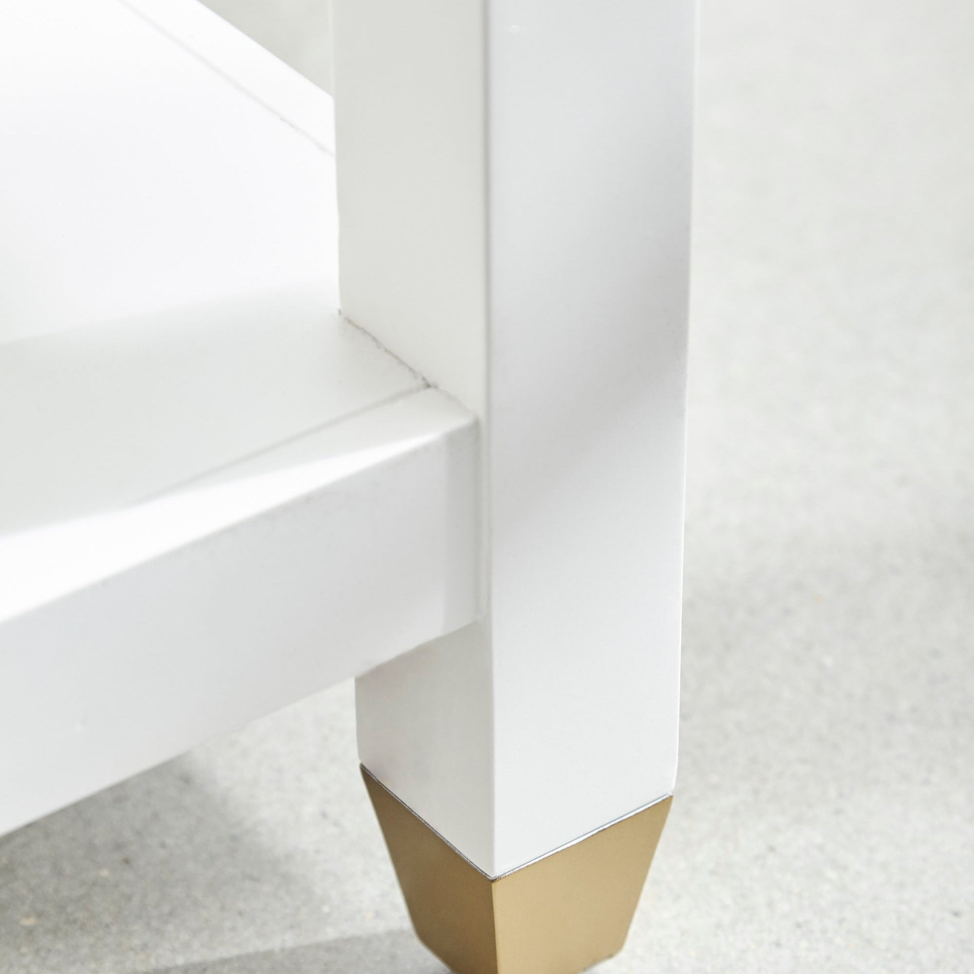 Close-up of Stella 1-Drawer Nightstand's matte white rubberwood leg with brushed brass foot by Essentials For Living.