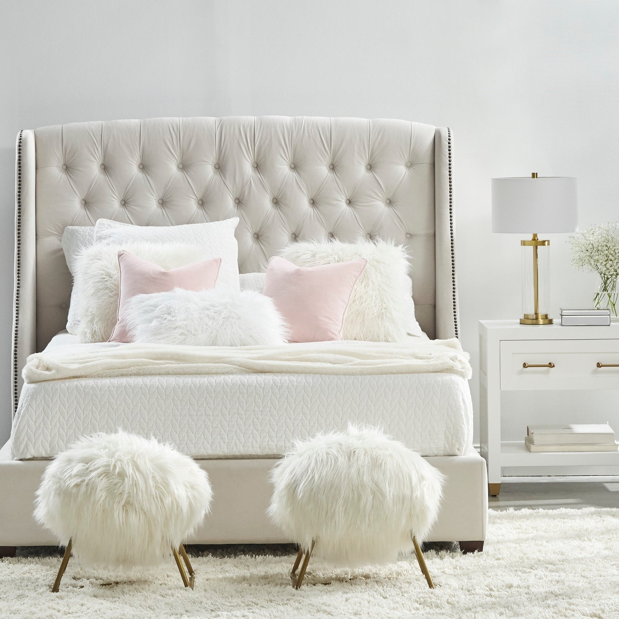 Essentials For Living Stella 1-Drawer Nightstand in matte white with brass hardware beside tufted bed in modern bedroom