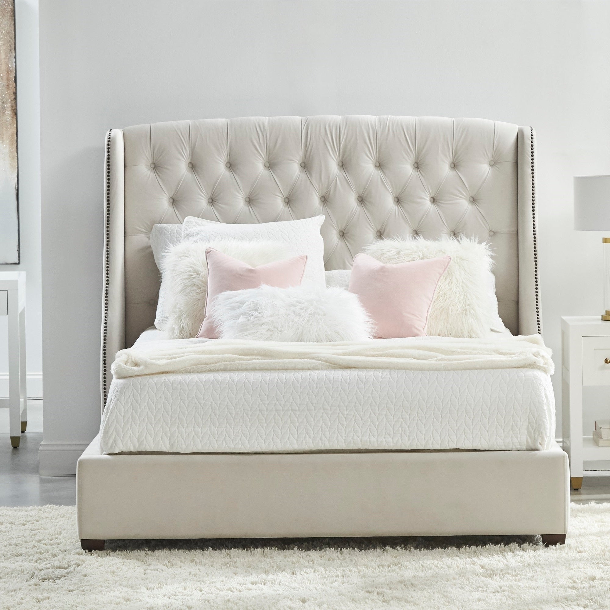 Upholstered beige bed with tufted headboard and soft pillows in a bright, modern bedroom setting