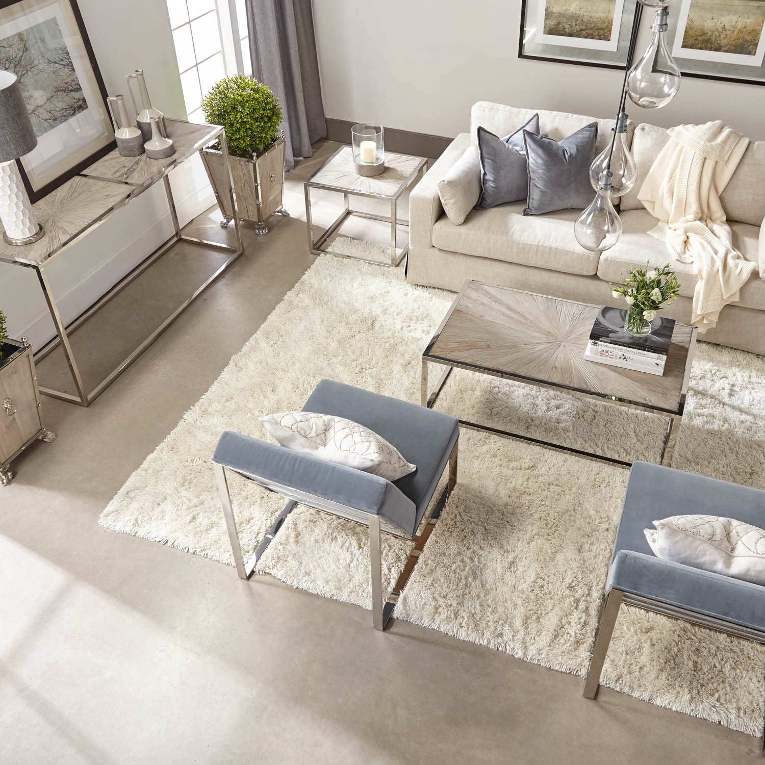 Modern living room with plush rug gray velvet chairs cream sofa and glass top tables with metal frames