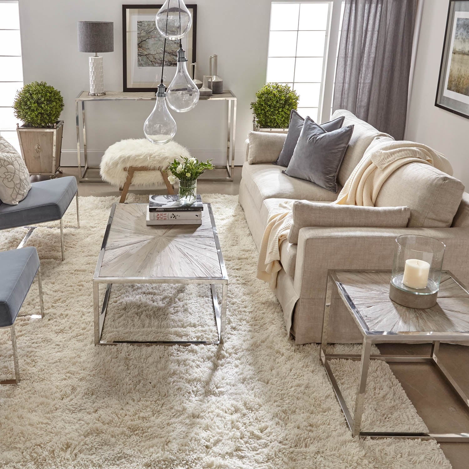 Neutral-toned living room with modern furniture, glass pendant lights, and soft textured rug creating a cozy atmosphere