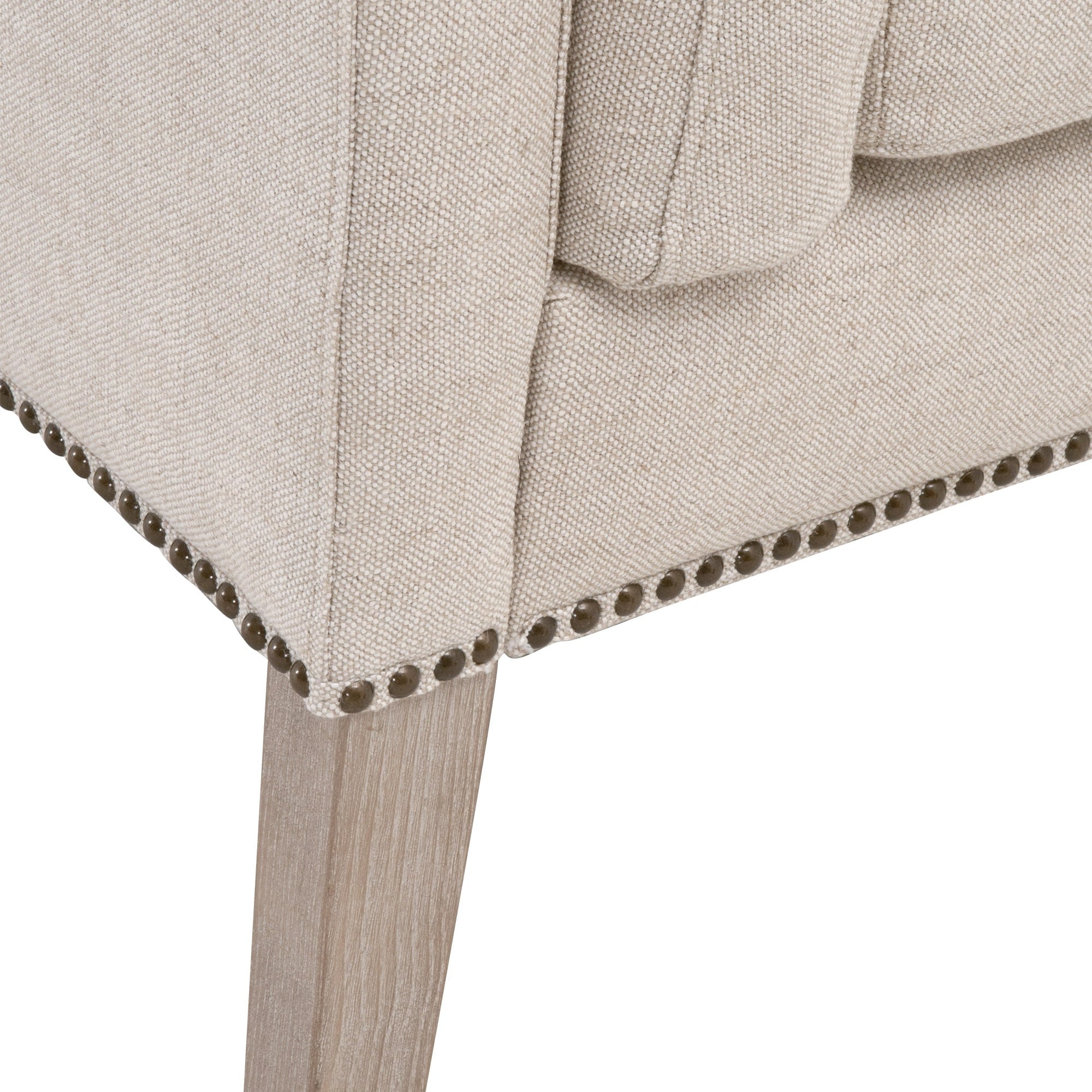 Close-up of Warner Bench leg in natural gray ash wood with Bisque French Linen upholstery and gold nail head trim detail