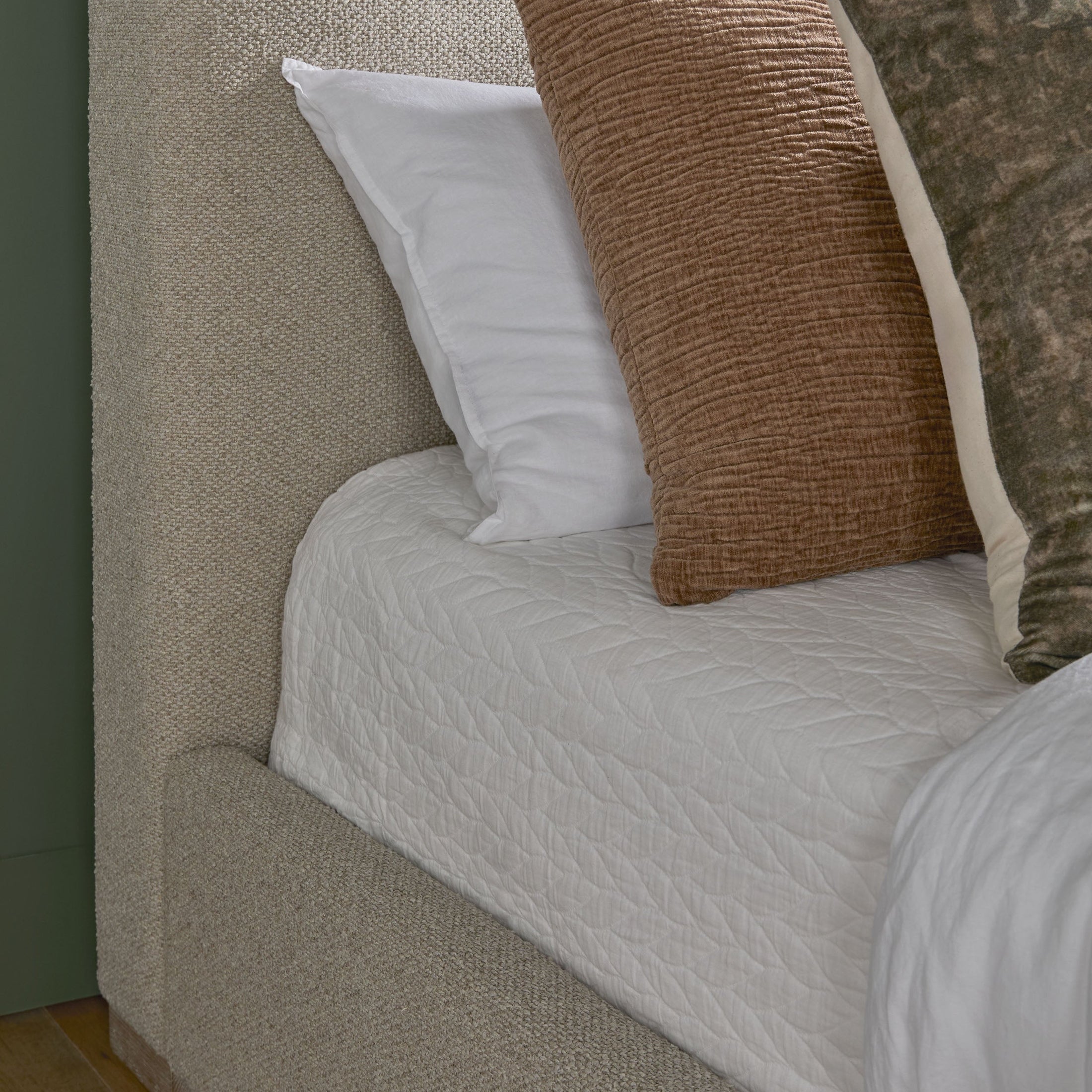 Close-up of Essentials for Living Warren Queen Bed upholstered in textured white boucle fabric with decorative pillows