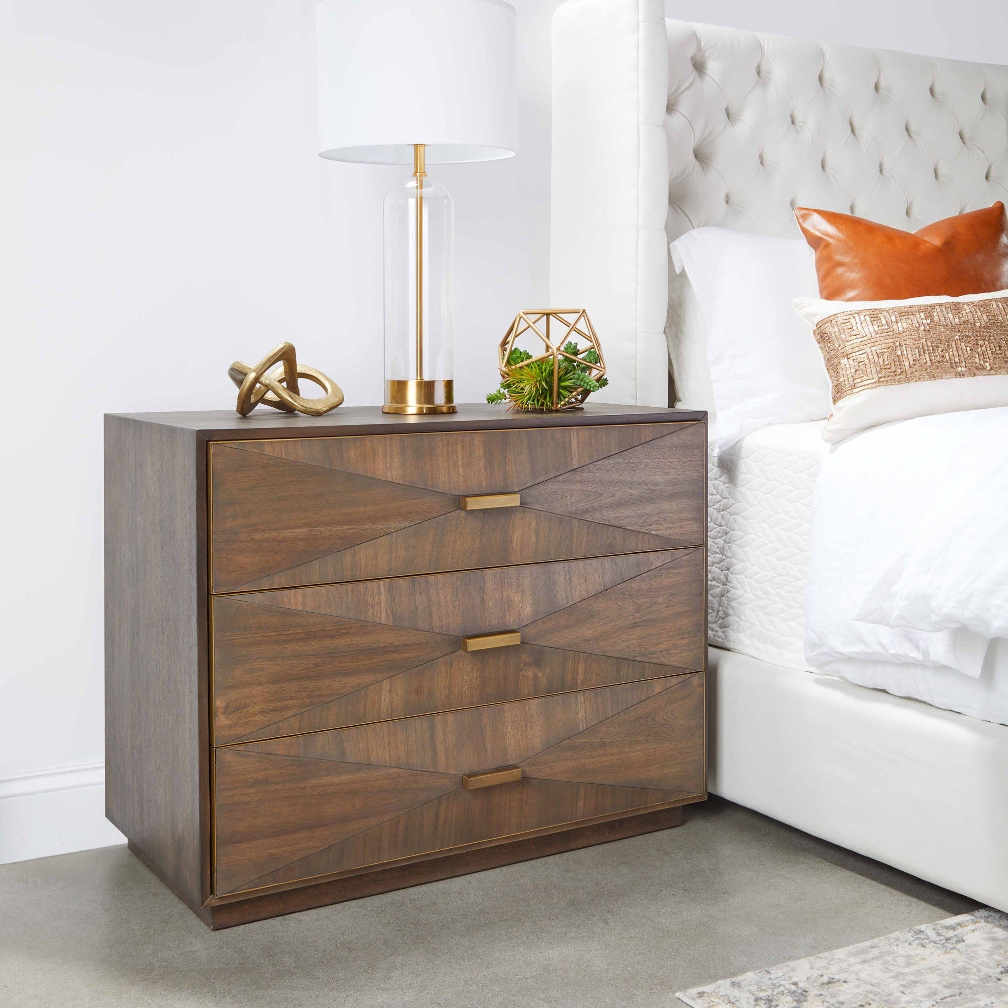 Wynn 3-drawer nightstand by Essentials For Living in burnished brown acacia veneer with brushed gold handles next to a bed