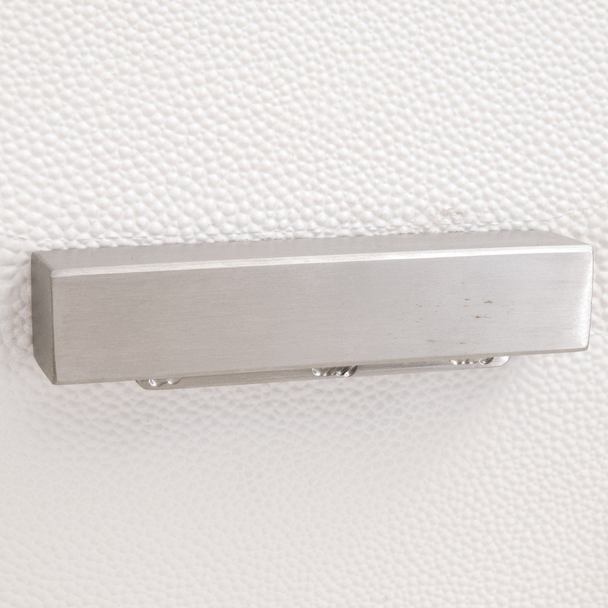 Brushed stainless steel drawer handle on pearl-white faux shagreen textured surface of Wynn nightstand drawer front