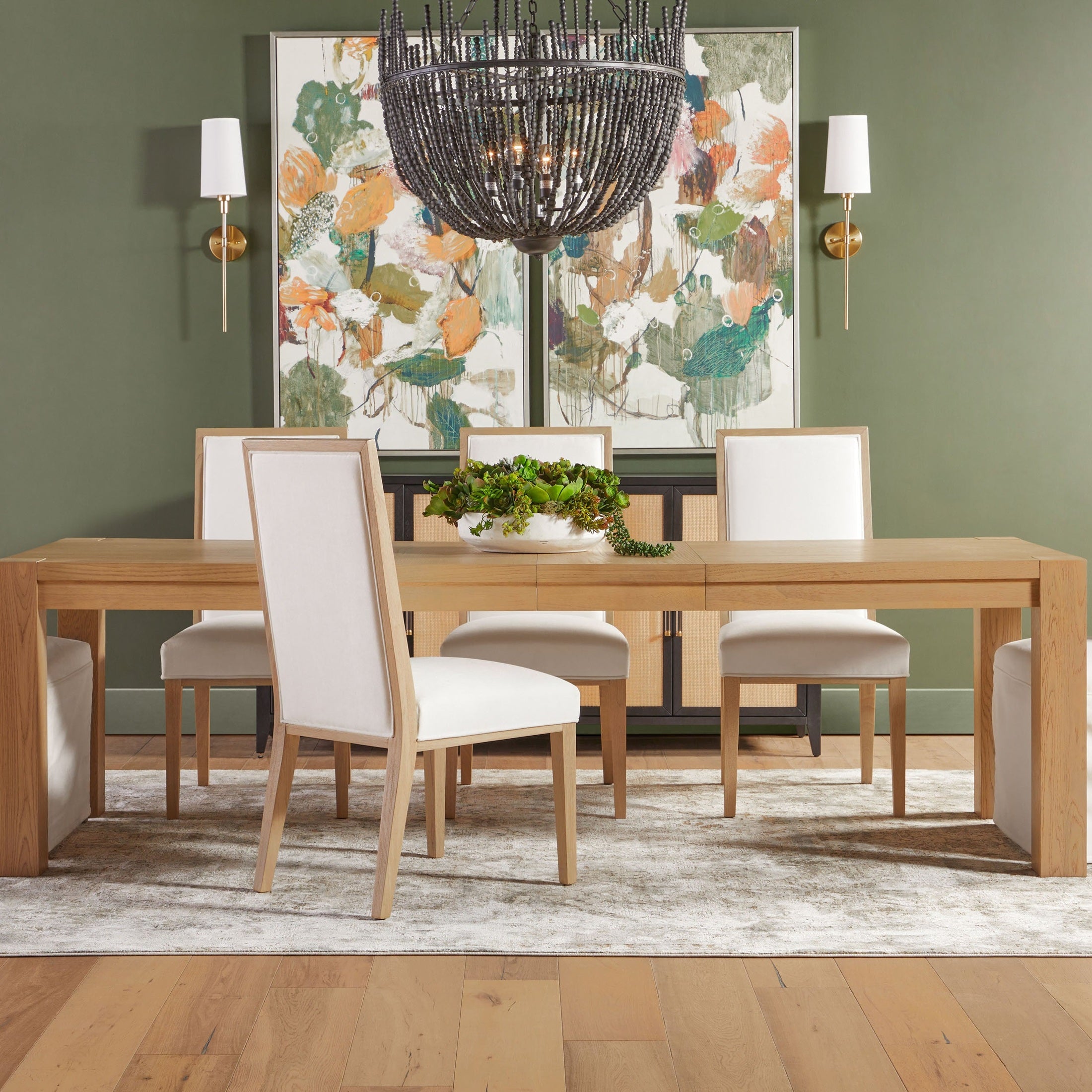 Adler Extension Dining Table in light honey oak with white chairs in dining room setup, Essentials for Living.