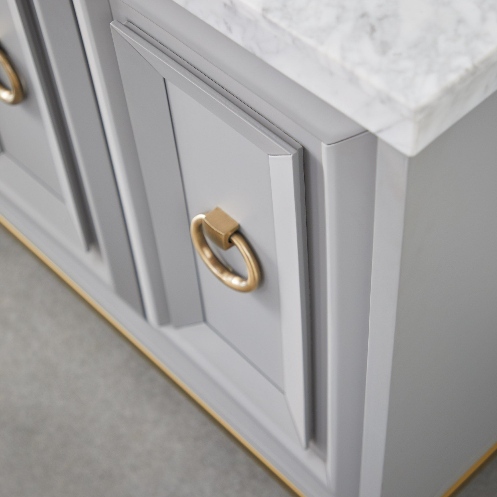 Close-up of brushed gold ring pull and gray lacquered cabinet door with Italian Carrera marble top on Azure Carrera Media Sideboard by Essentials for Living