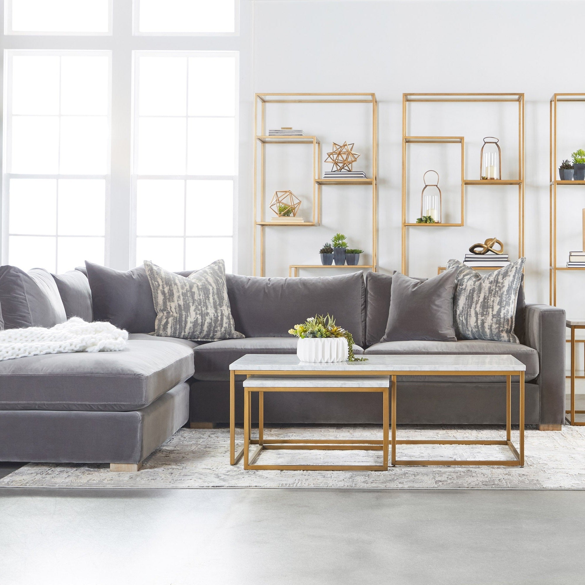 Beakman Bookcase with brass metal frame and clear glass shelves in modern living room by Essentials for Living