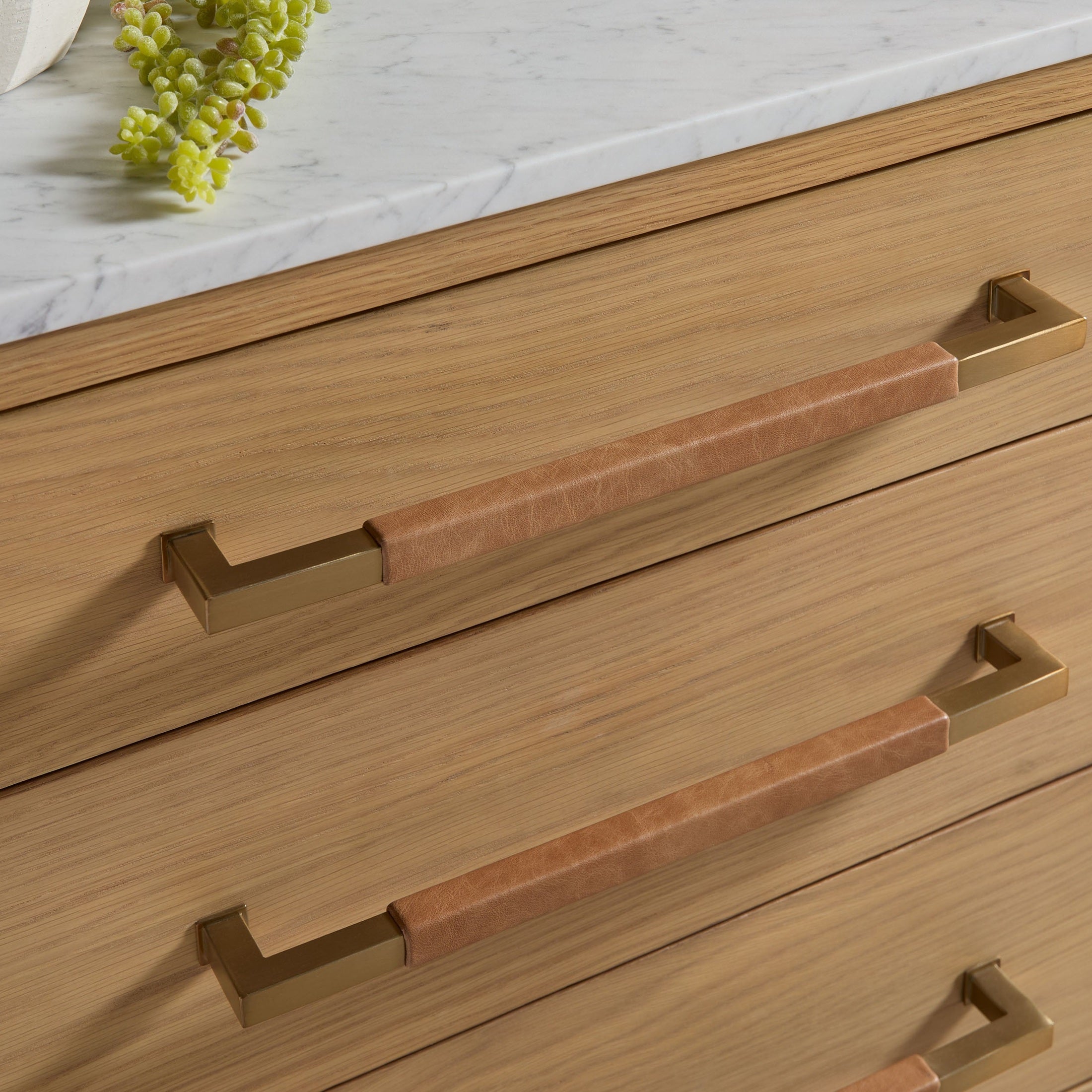 Close-up of aged brass drawer pulls on Cambria 8-Drawer Double Dresser with Bianco marble top by Essentials For Living
