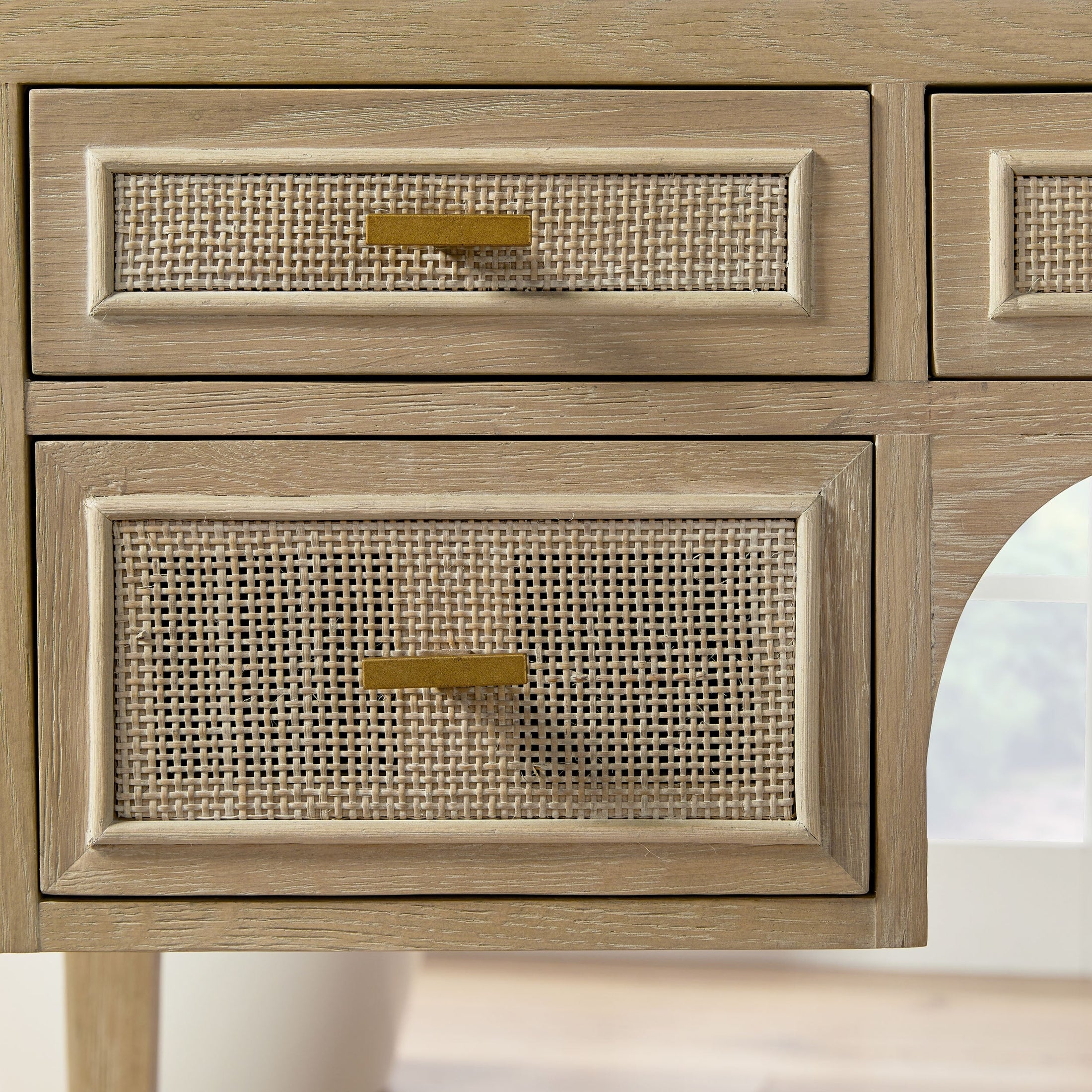 Close-up of smoke gray oak desk drawers with natural cane inlay and brass handles by Essentials for Living