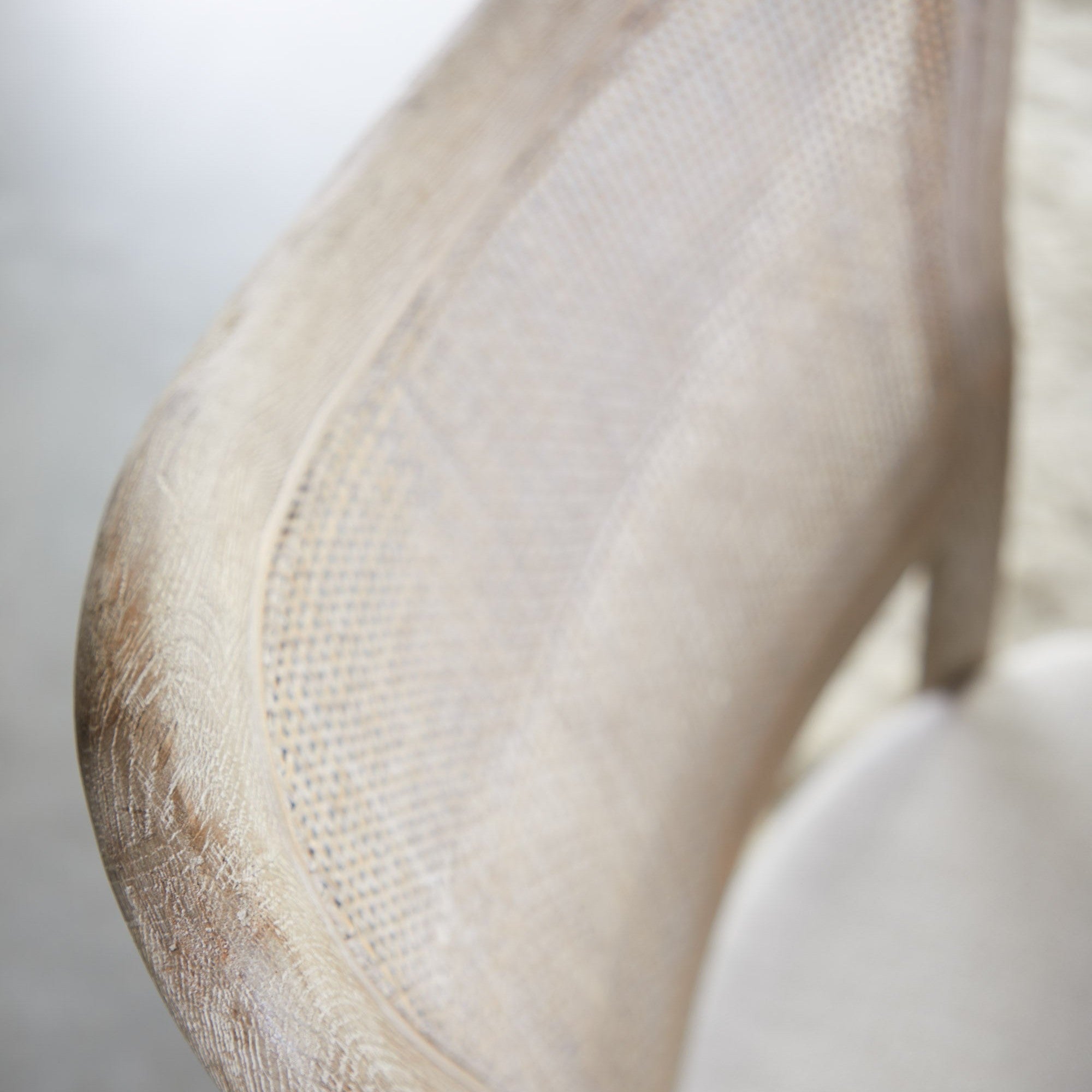 Close-up of solid oak frame and handwoven cane backrest on a bisque upholstered dining chair by Essentials For Living