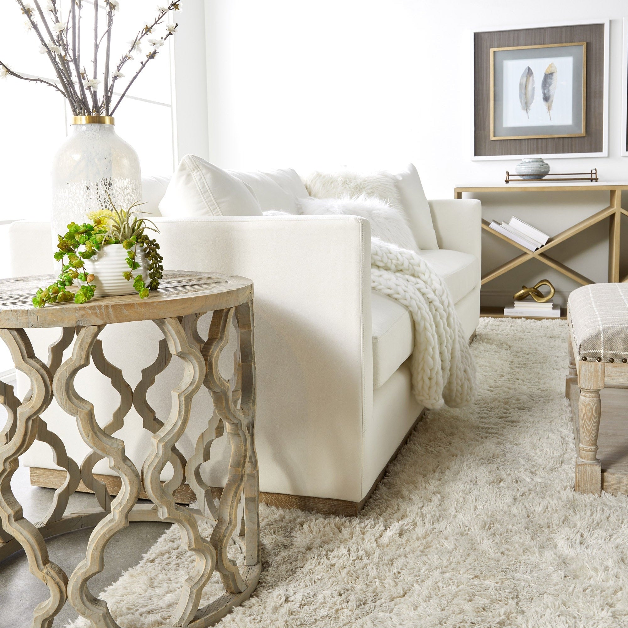 Bright living room featuring a white sofa, decorative wooden side table, plush rug, and artwork on the wall